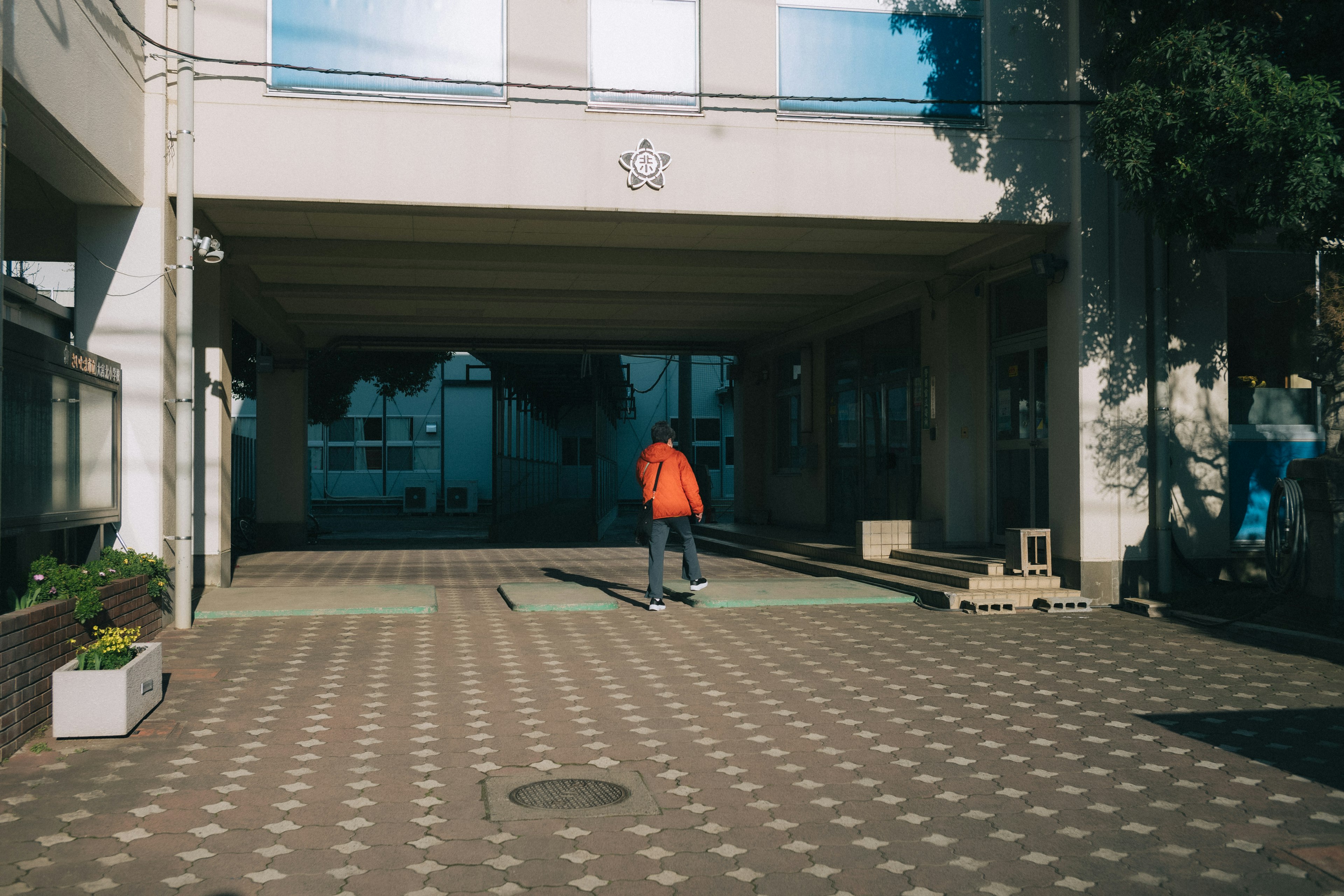 A person in an orange outfit walking towards a building entrance