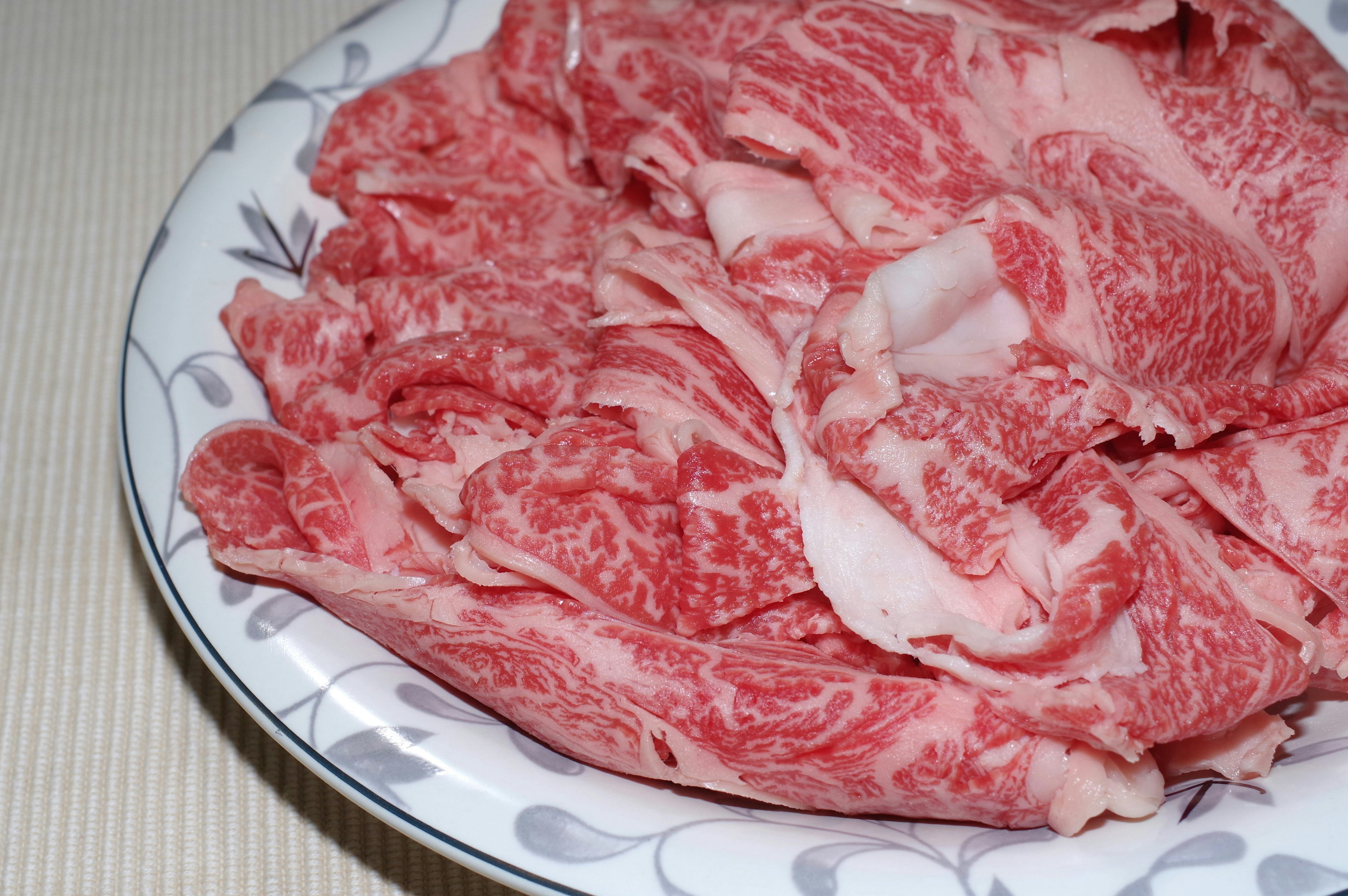 Thinly sliced marbled Wagyu beef arranged on a white plate