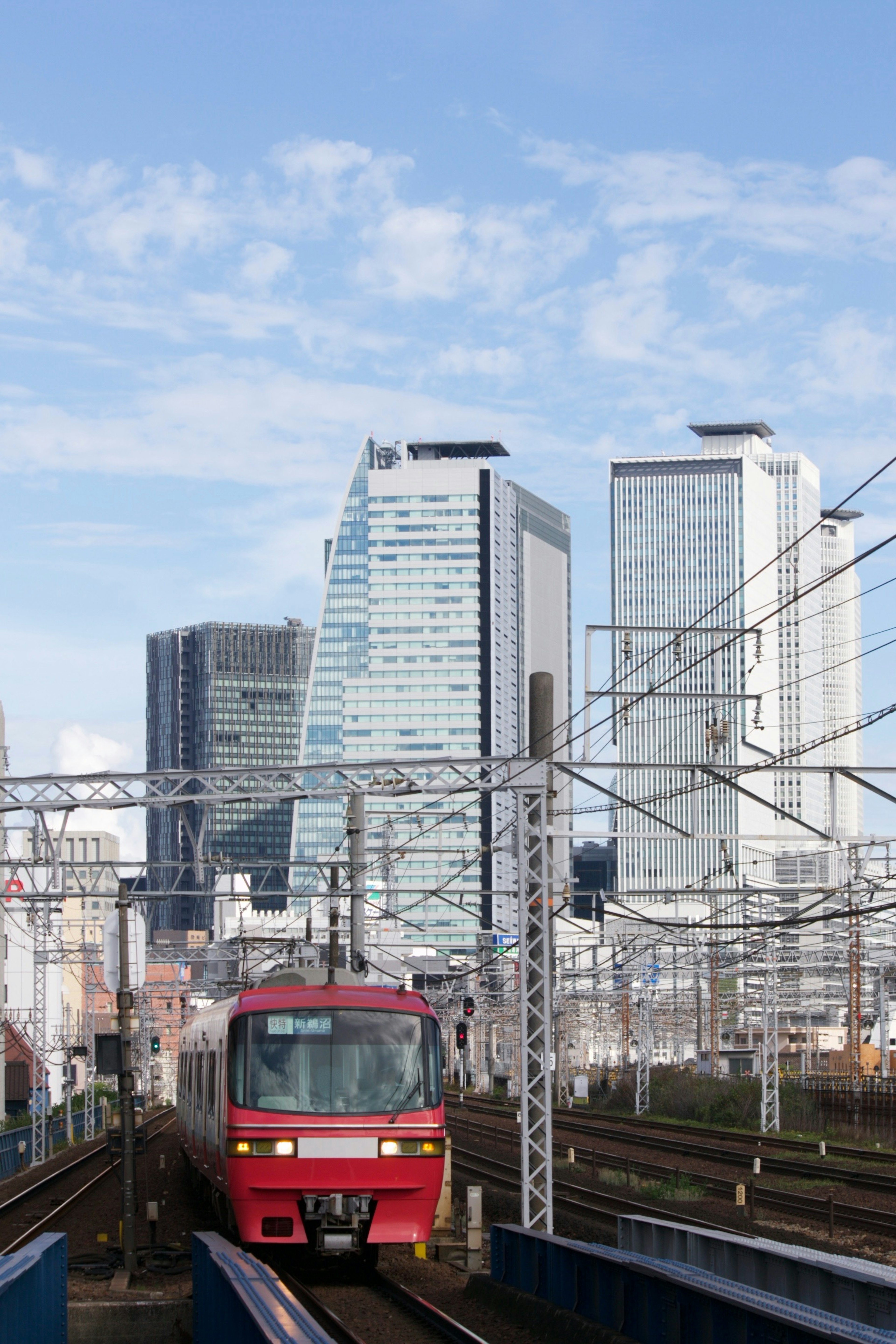 Red train traveling among skyscrapers