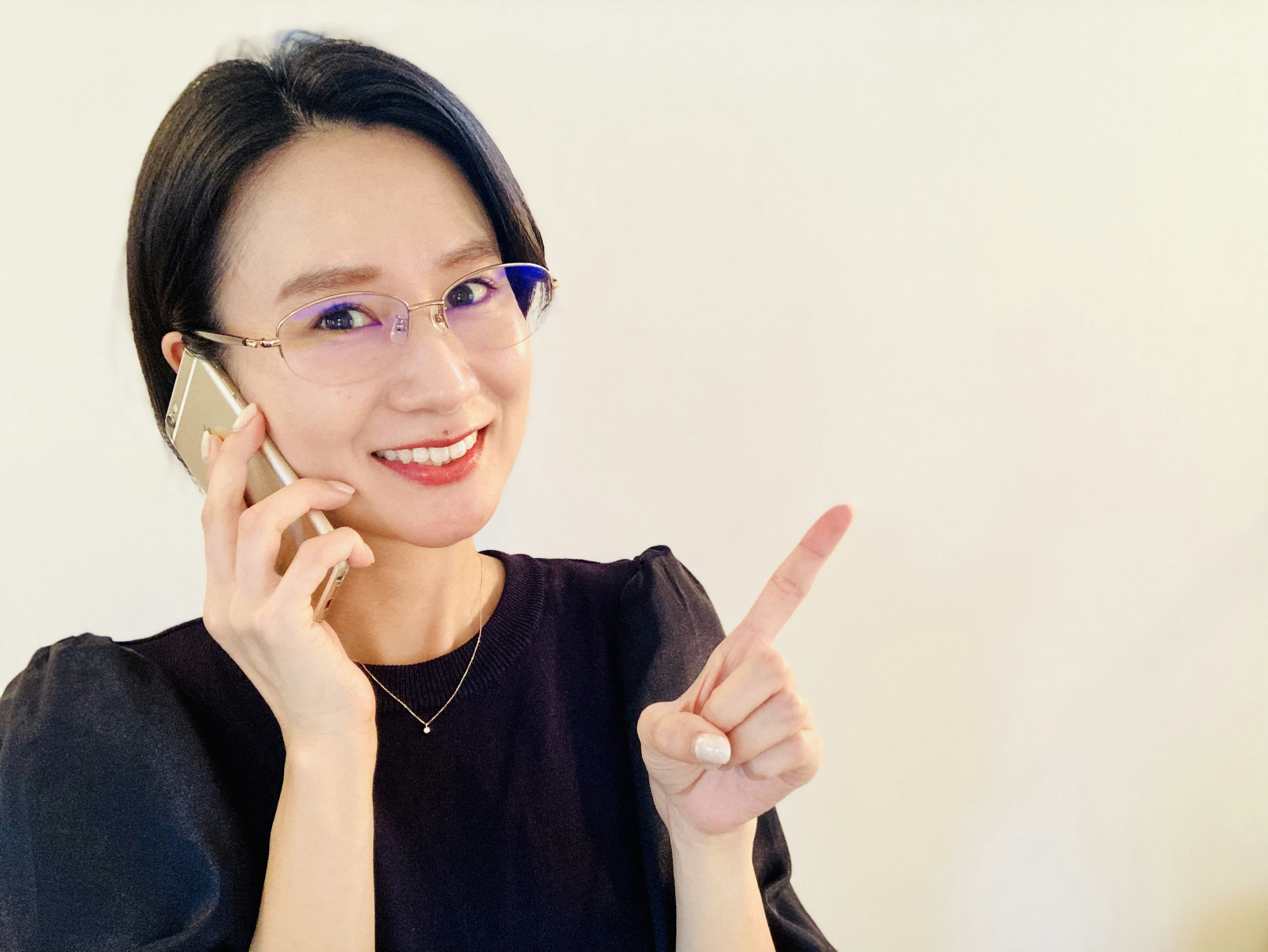 Woman smiling while talking on the phone pointing her finger