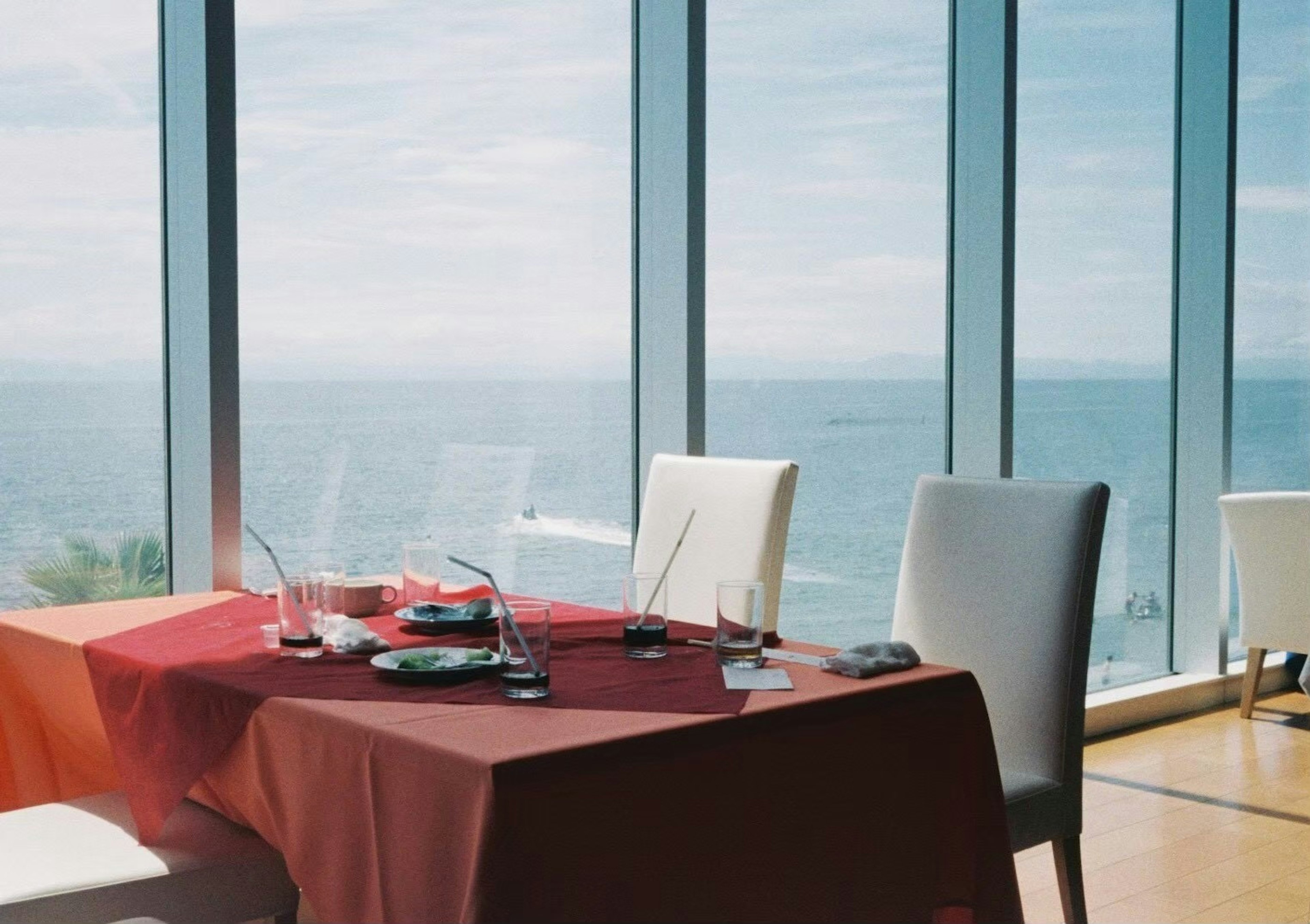 Tavolo di ristorante con vista sul mare tovaglia rossa e sedie bianche