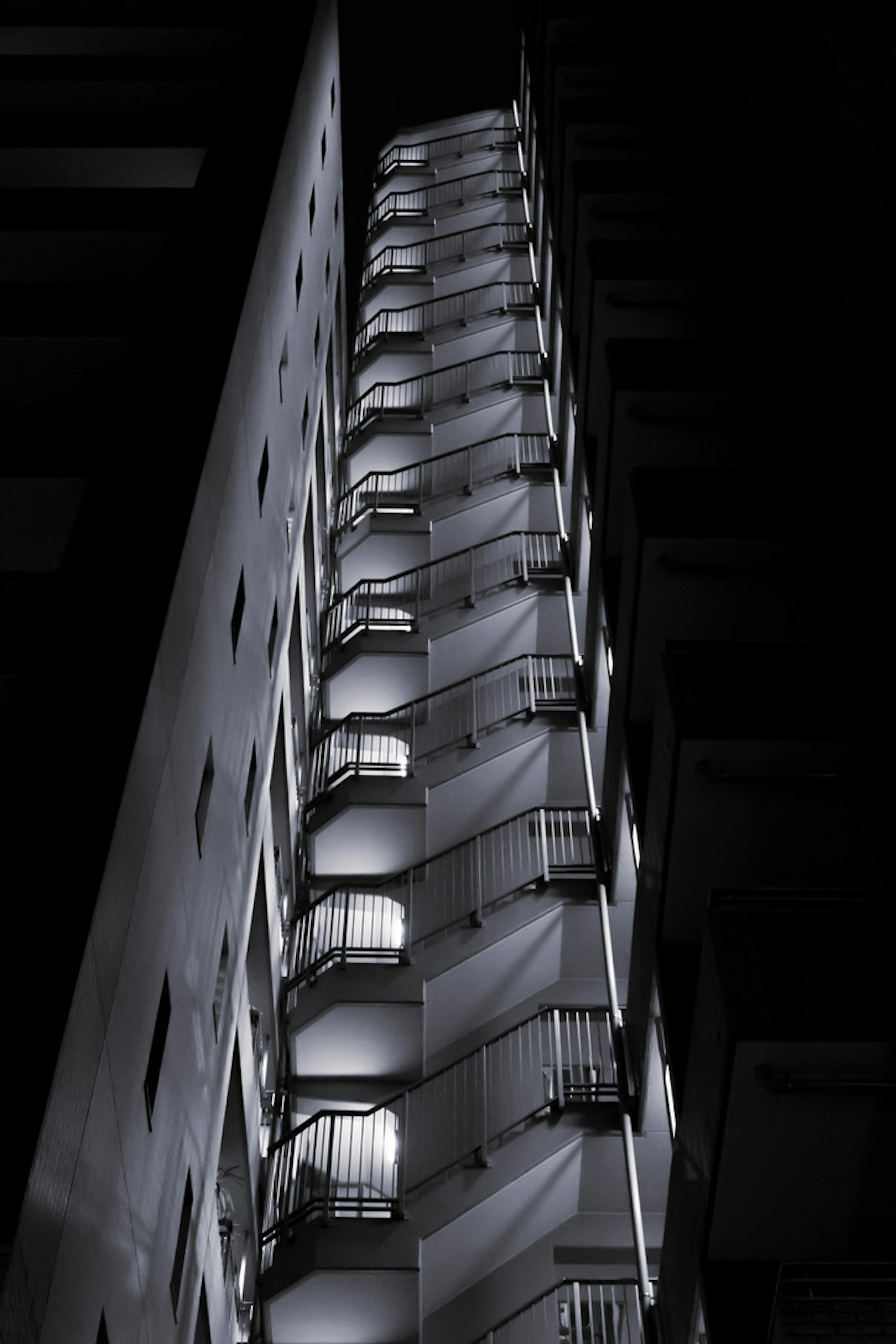 Vue extérieure d'un bâtiment en escalier la nuit avec des balcons illuminés