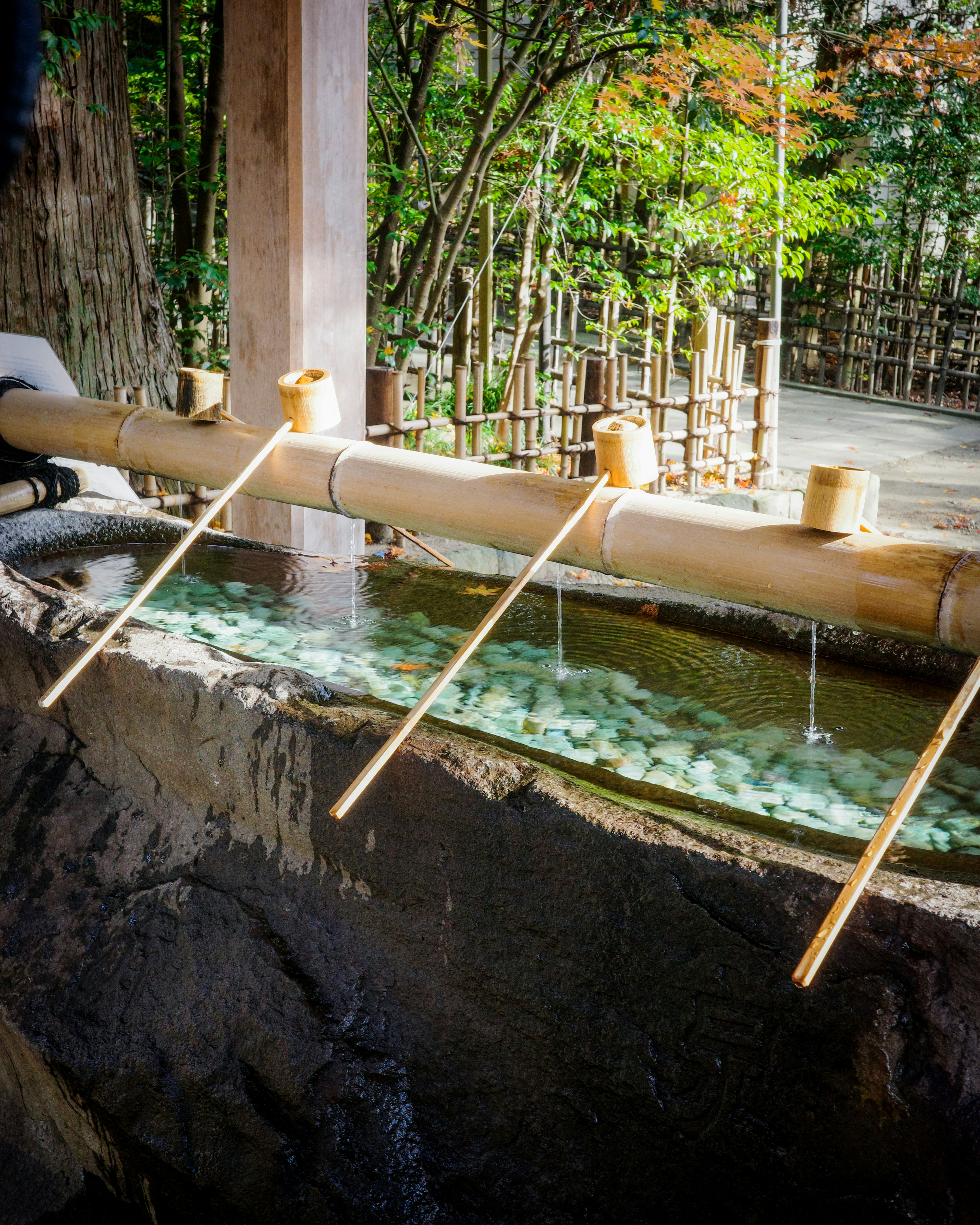 Escena de jardín japonés con caños de bambú y un lavabo de piedra