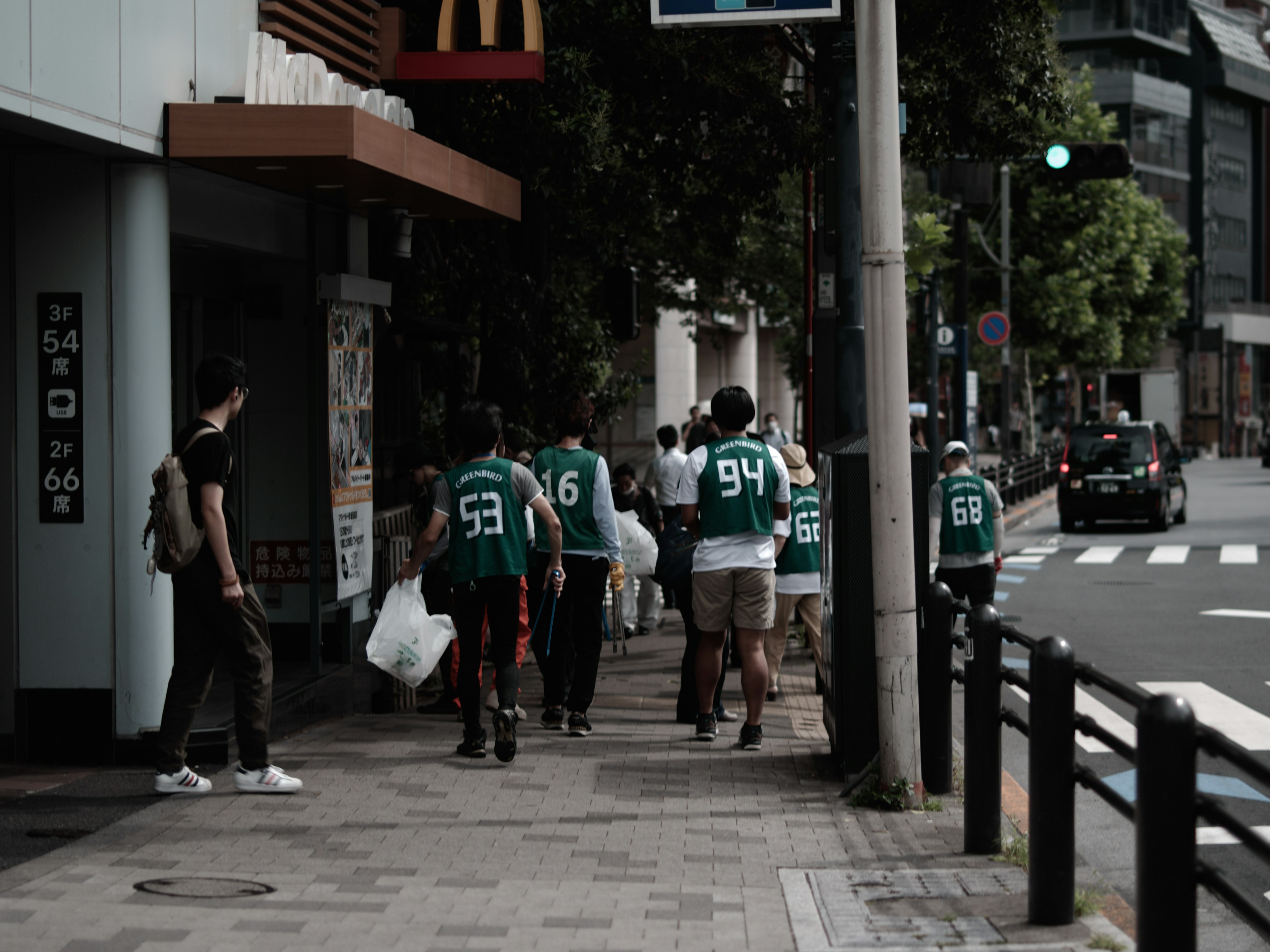 Sekelompok orang berpakaian jersey hijau berjalan di trotoar