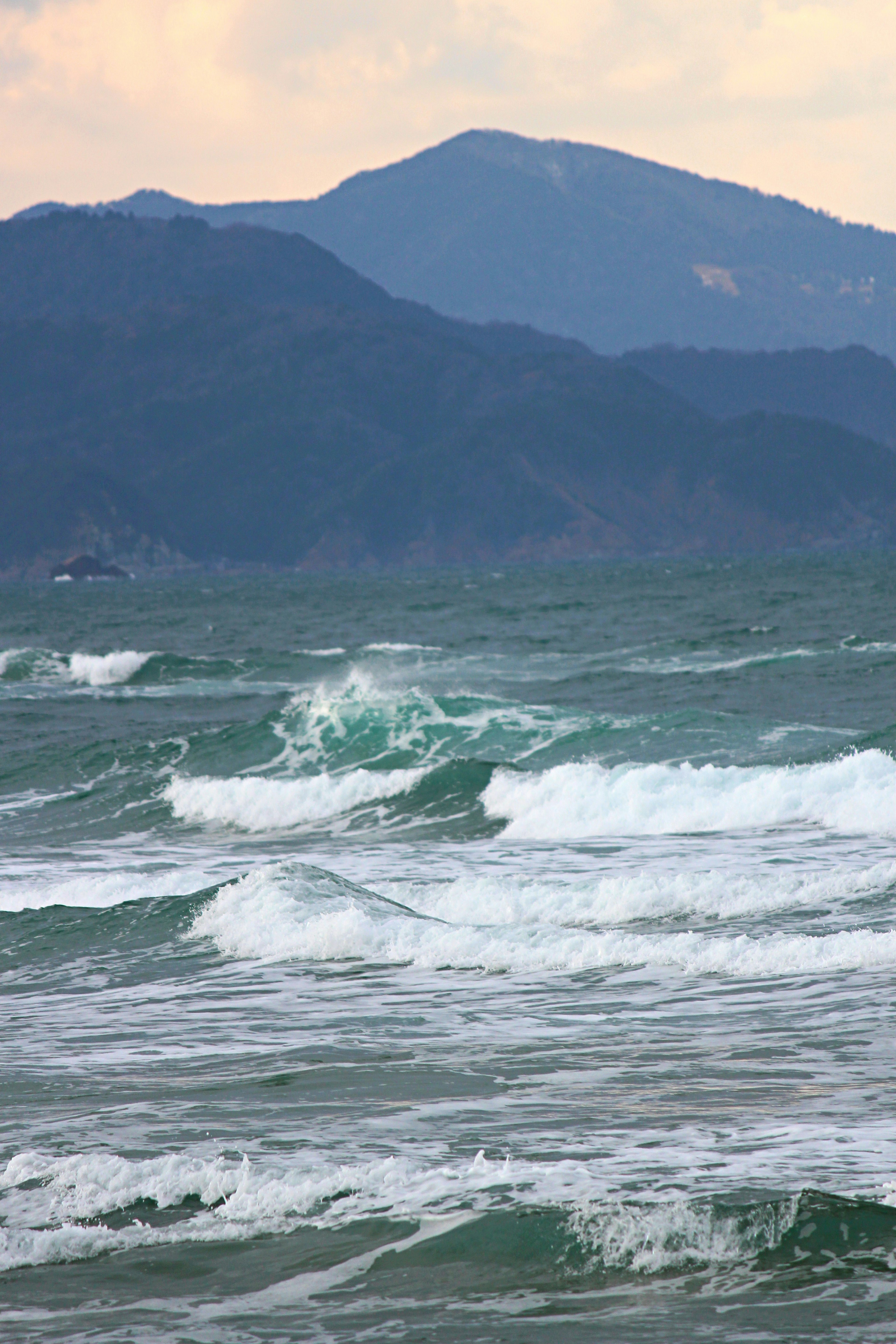 蓝色海洋波浪的风景，背景是山脉