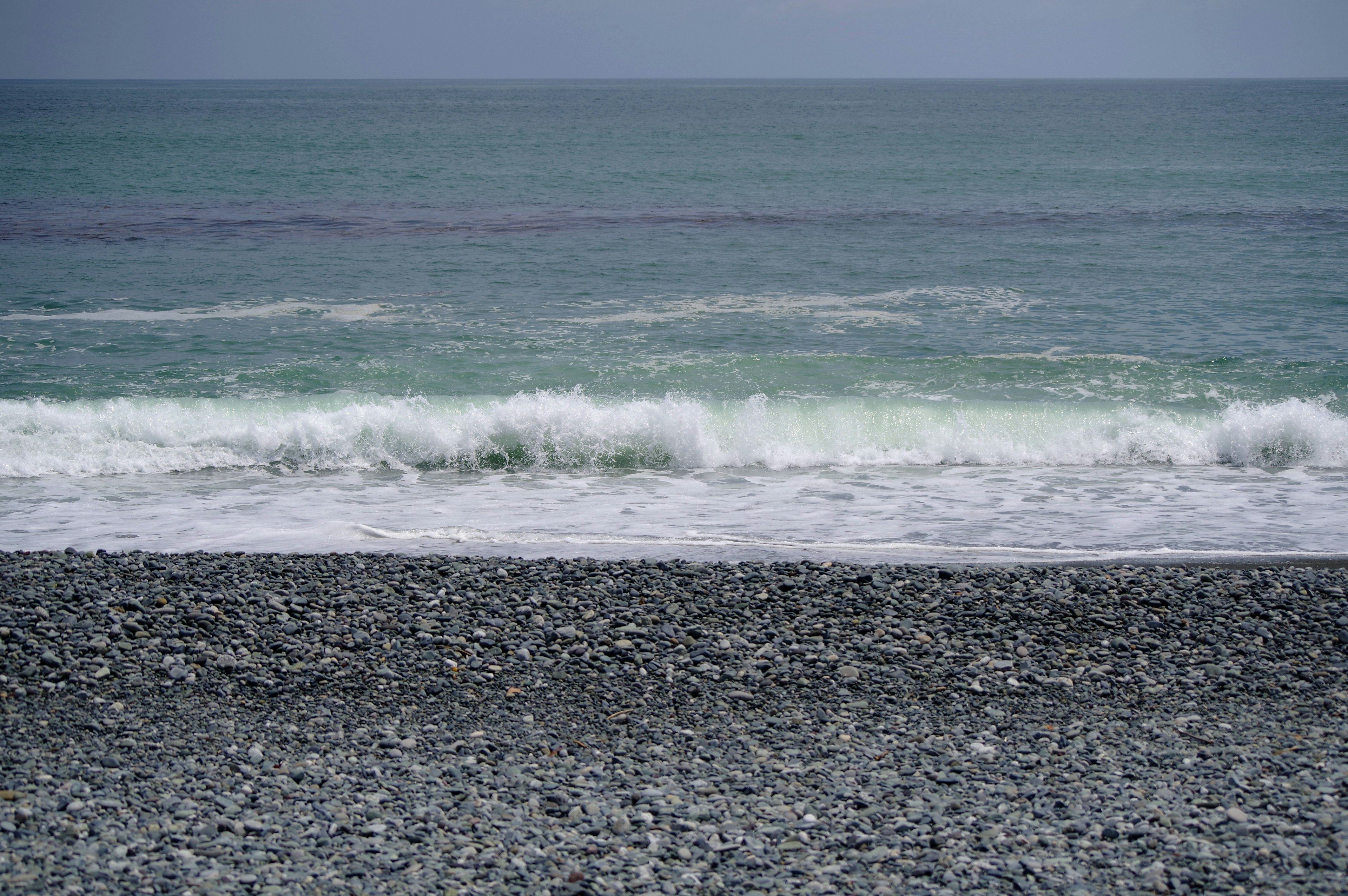 Onde del mare calme e paesaggio di spiaggia di ciottoli