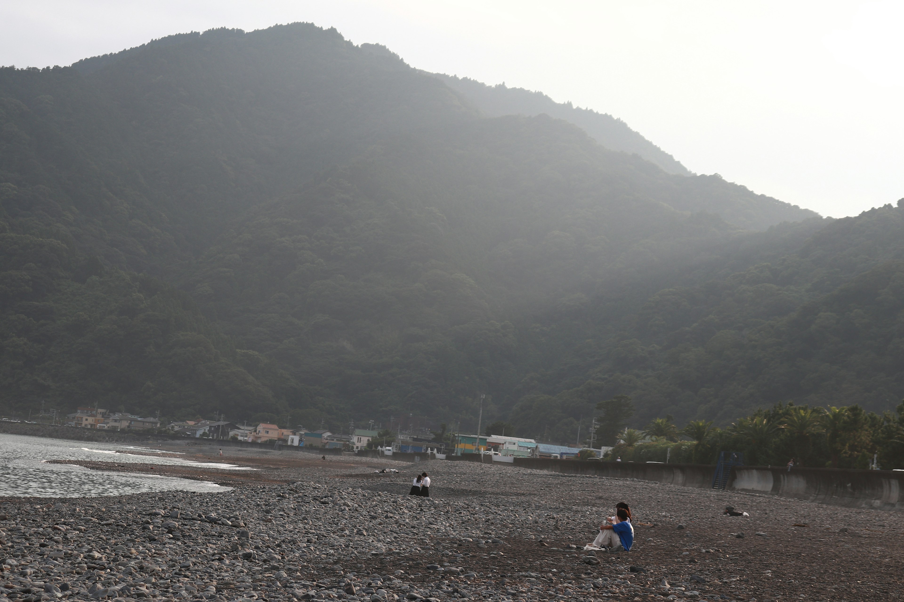 人們在岩石海灘上，背景是山脈