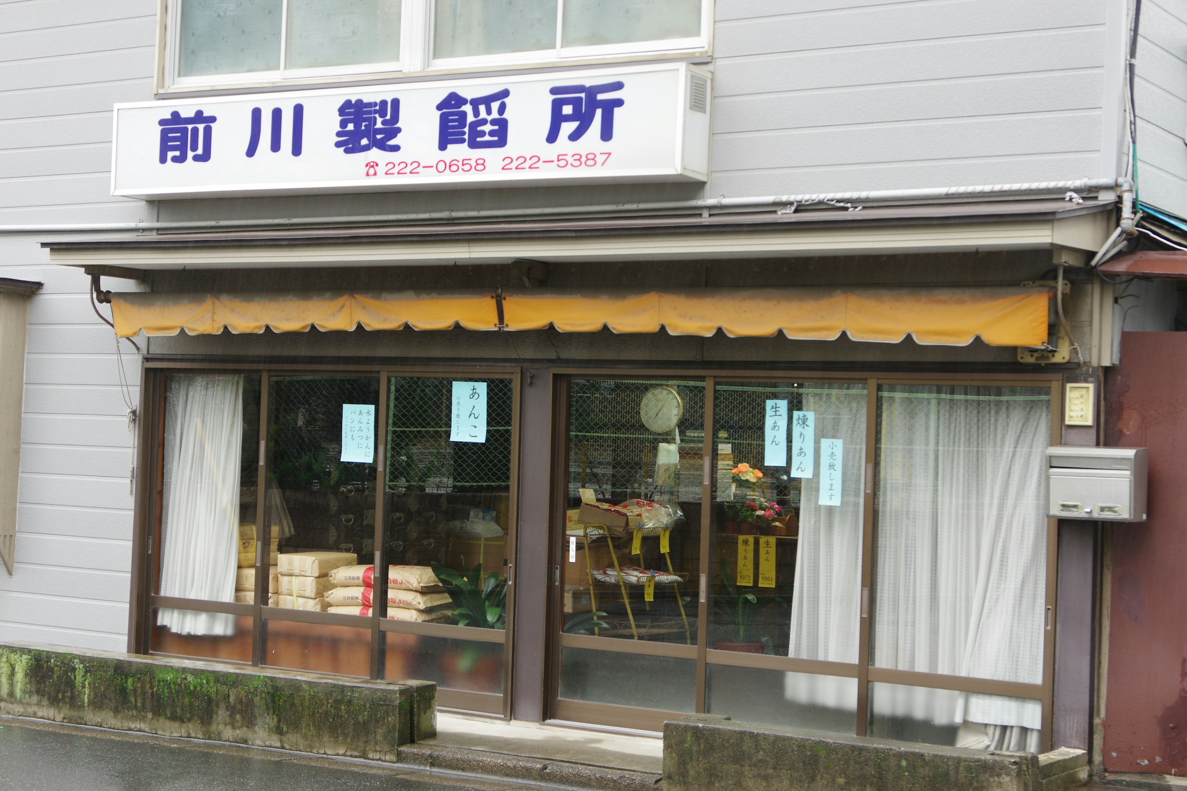 Fachada de Maekawa Seiansho con toldo brillante y ventanas de vidrio