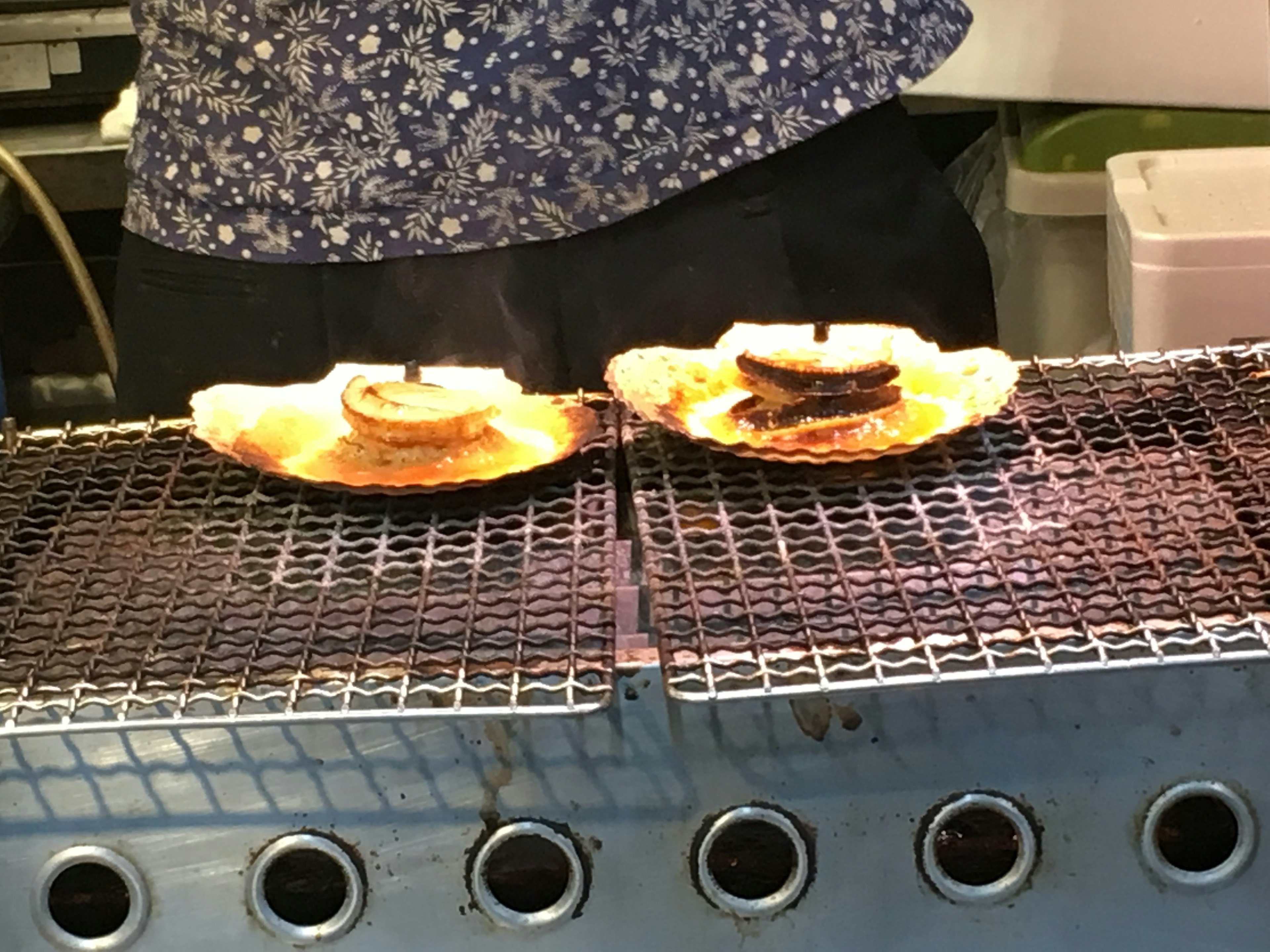 Dos platos con platos a la parrilla en una parrilla de fondo con una persona en camisa de flores