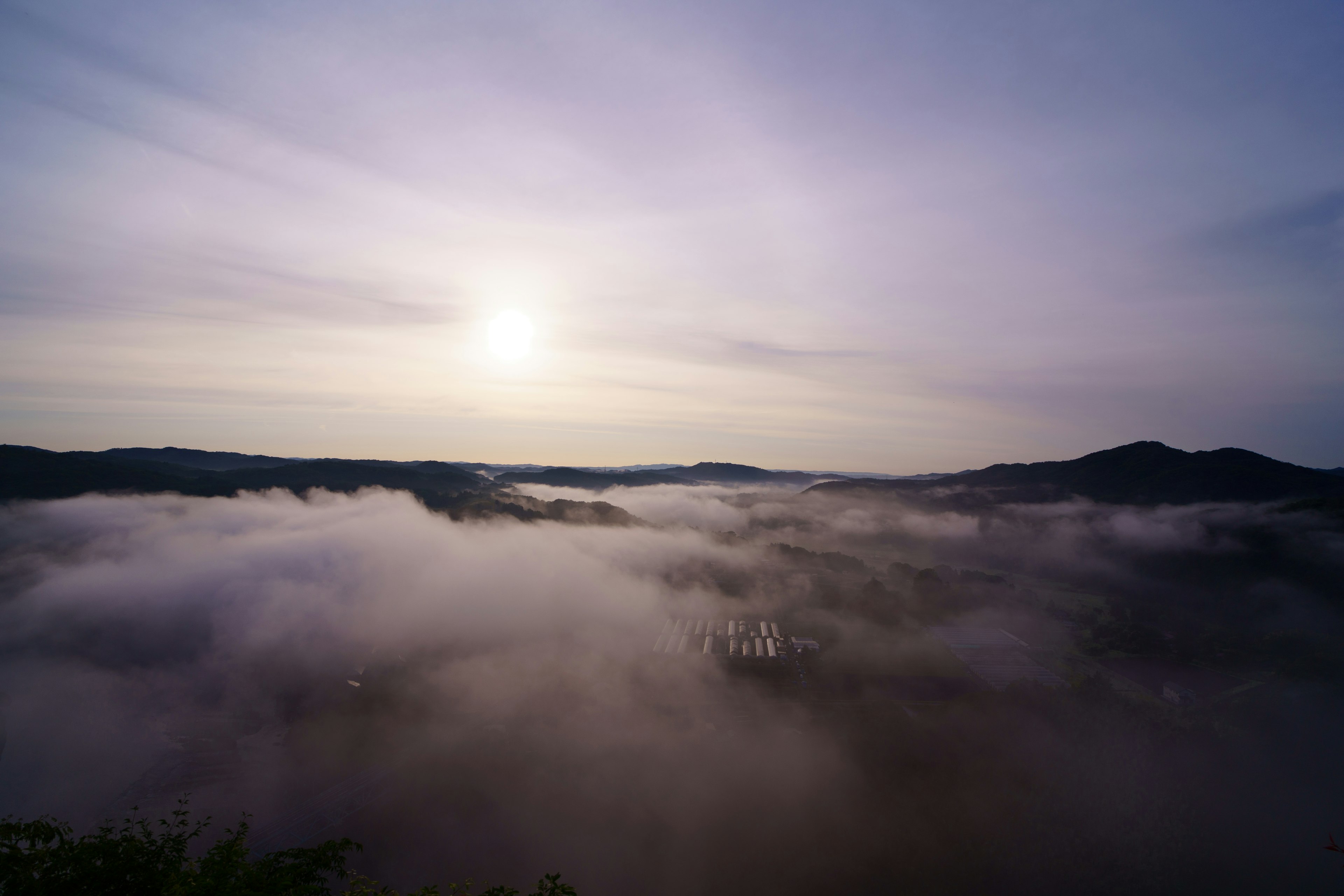 Gunung yang diselimuti kabut dengan matahari terbit yang tenang