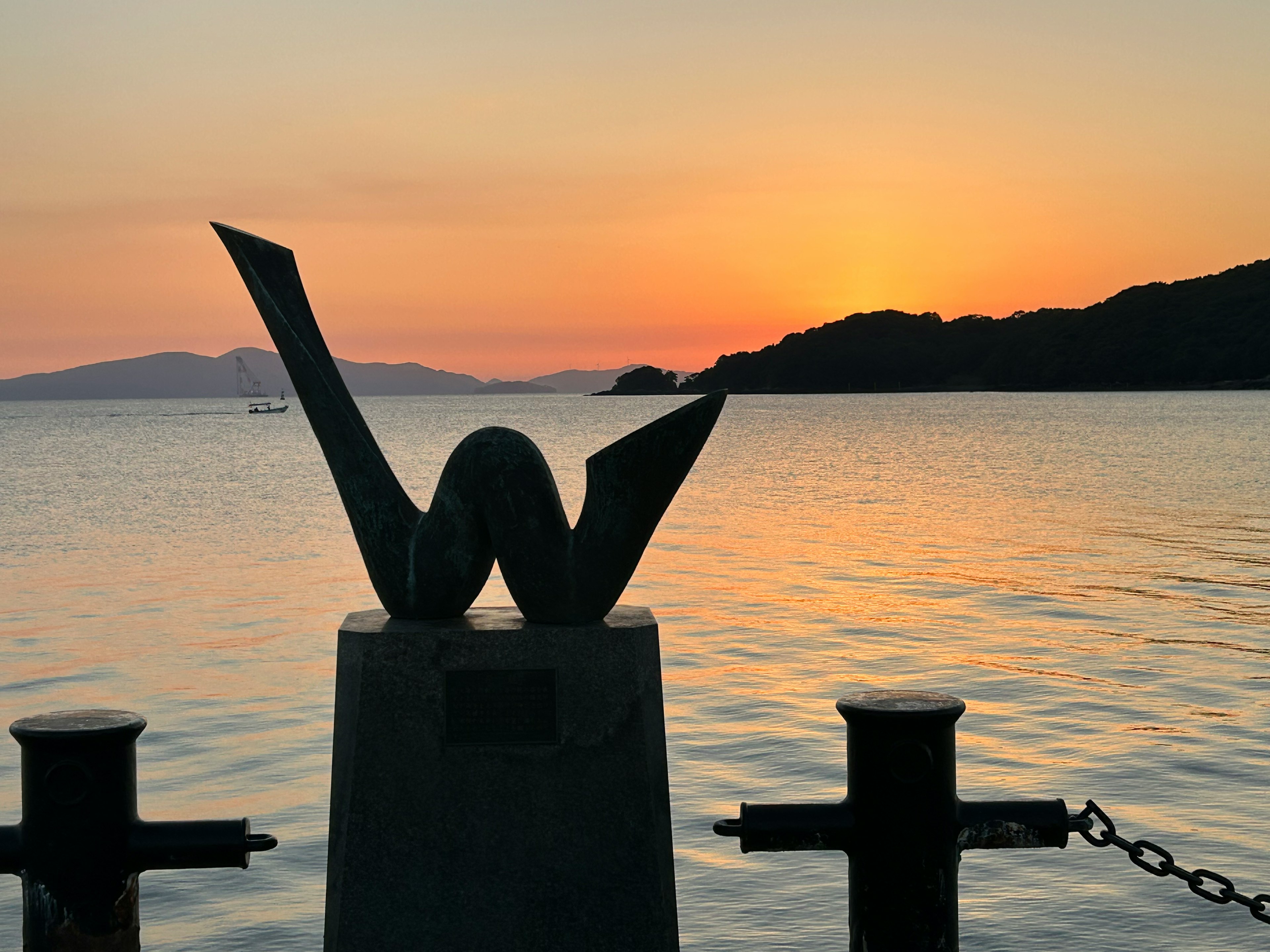 美しい夕焼けの中に立つ抽象的な彫刻と海の景色