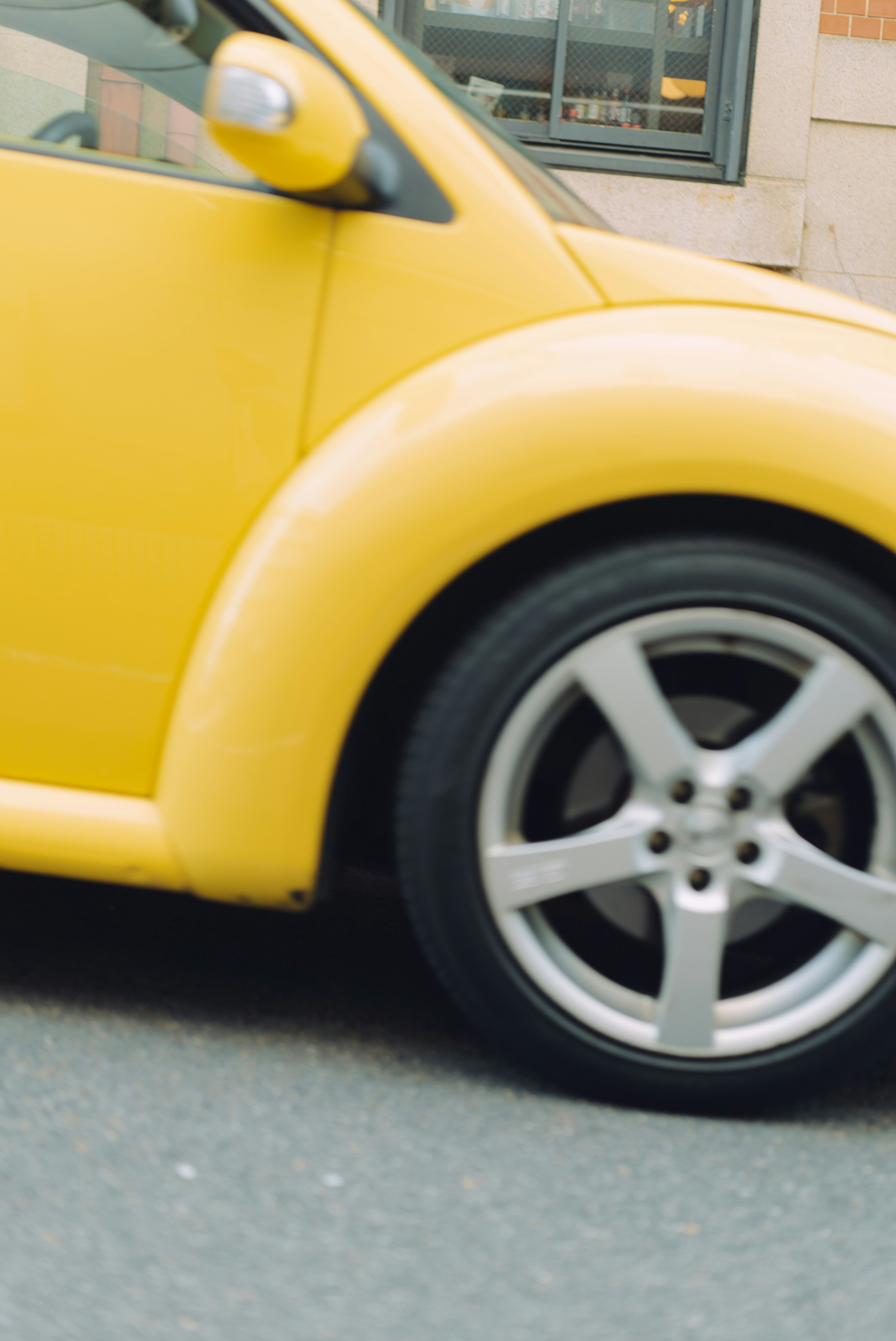 Primer plano de un coche amarillo mostrando el lado y la rueda