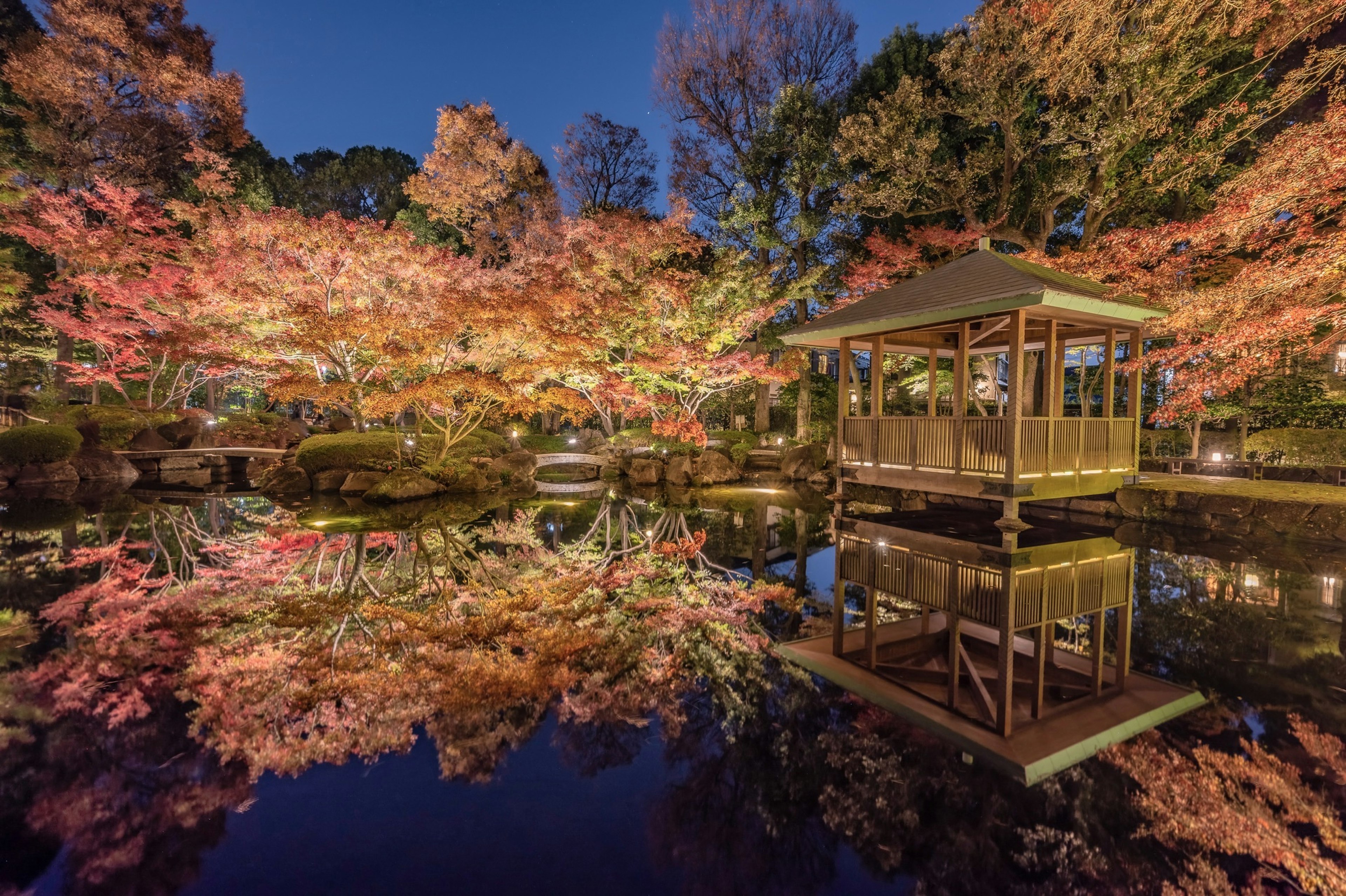 美しい紅葉の反射がある池と小屋の風景