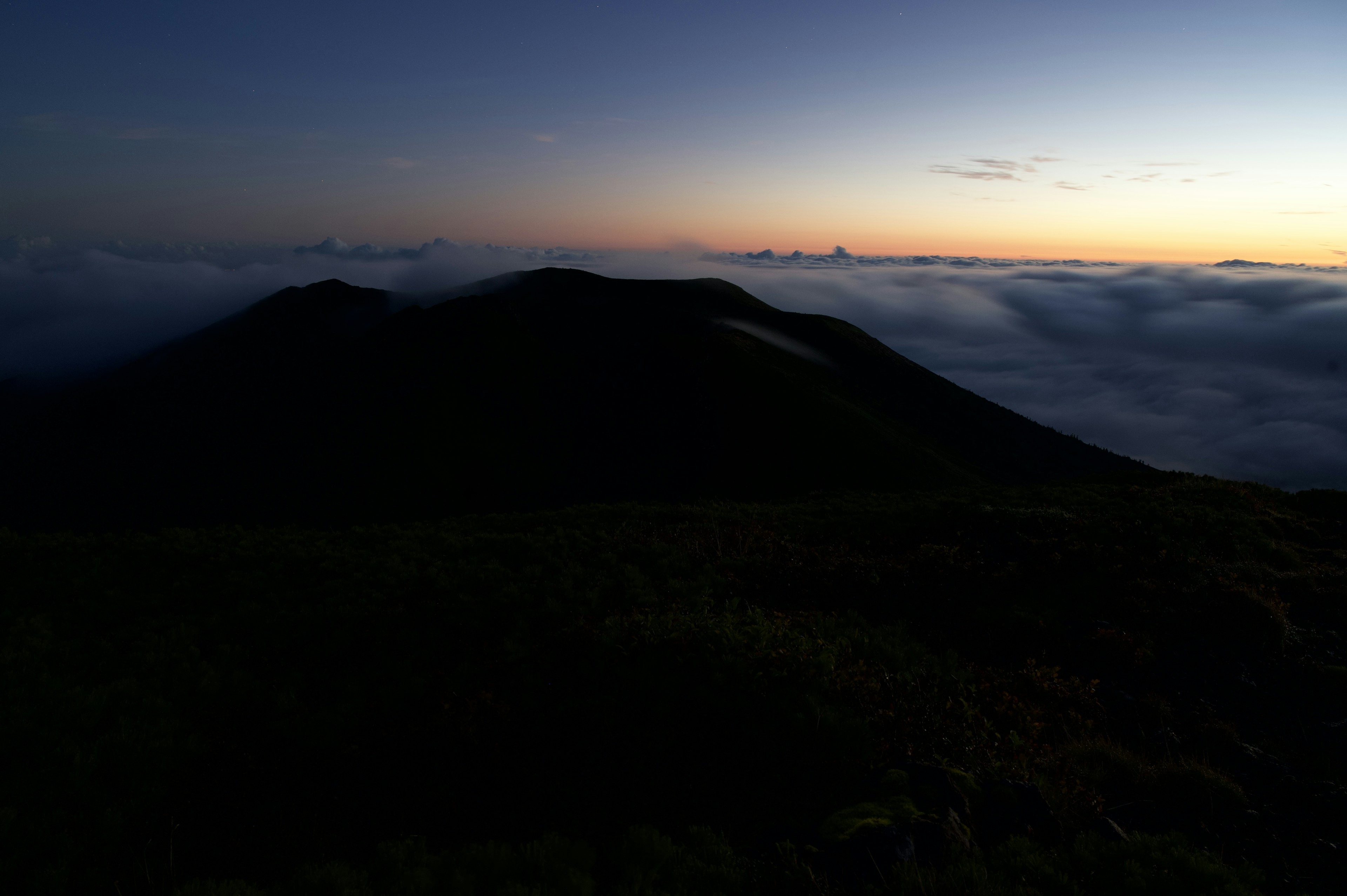 雲海の上に沈む夕日と山のシルエット