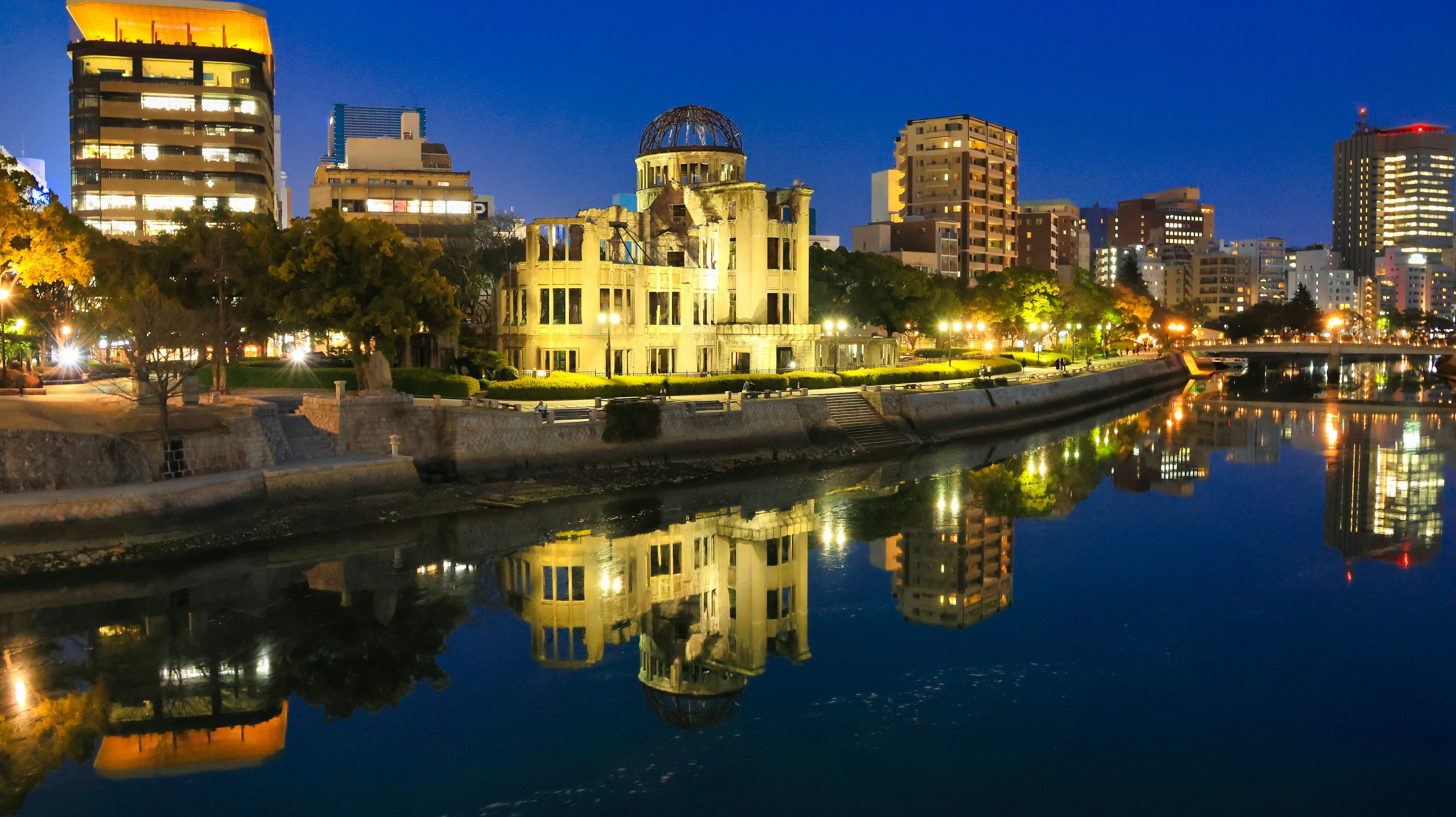 Historisches Gebäude am Flussufer mit modernen Wolkenkratzern, die sich nachts im Wasser spiegeln