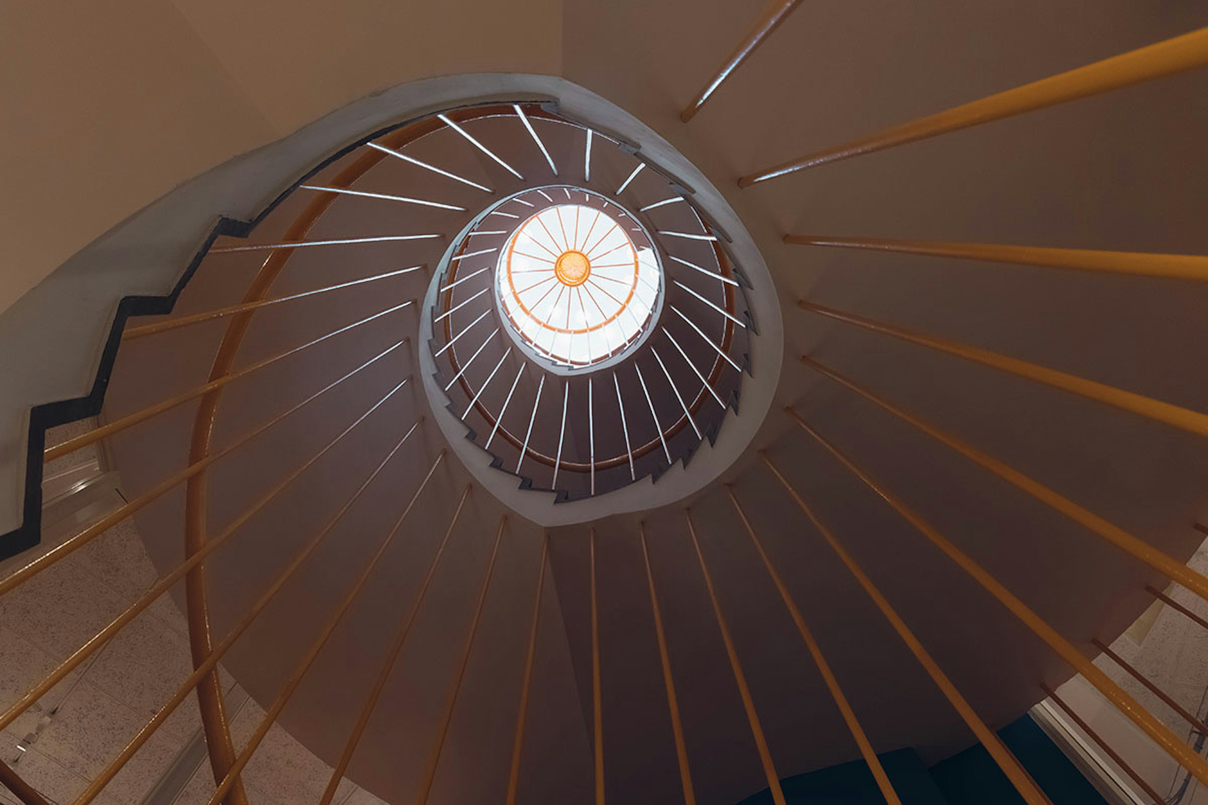 Vista desde arriba de una escalera de caracol con una luz circular brillante en el centro