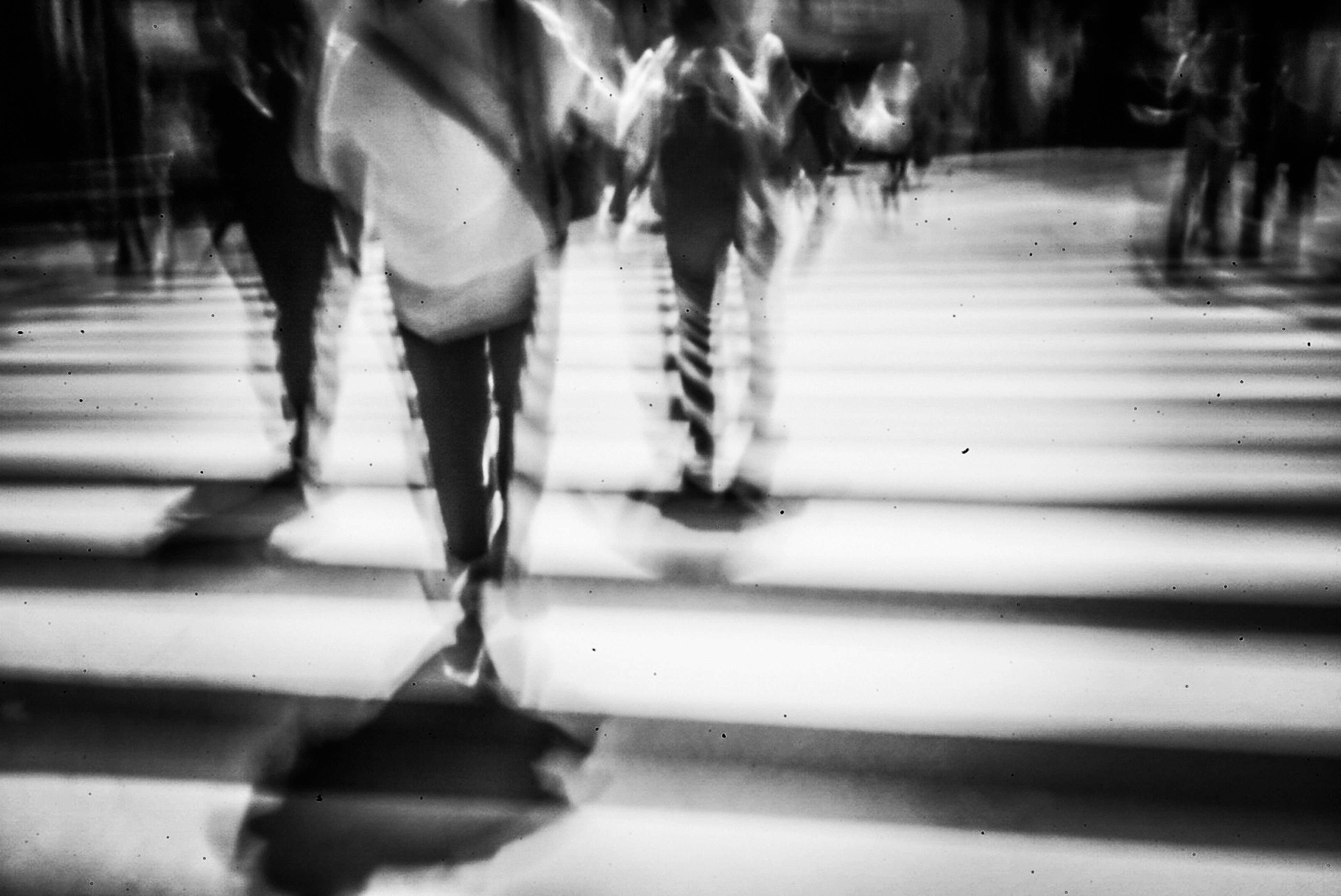 Personas cruzando un paso de peatones en blanco y negro en movimiento