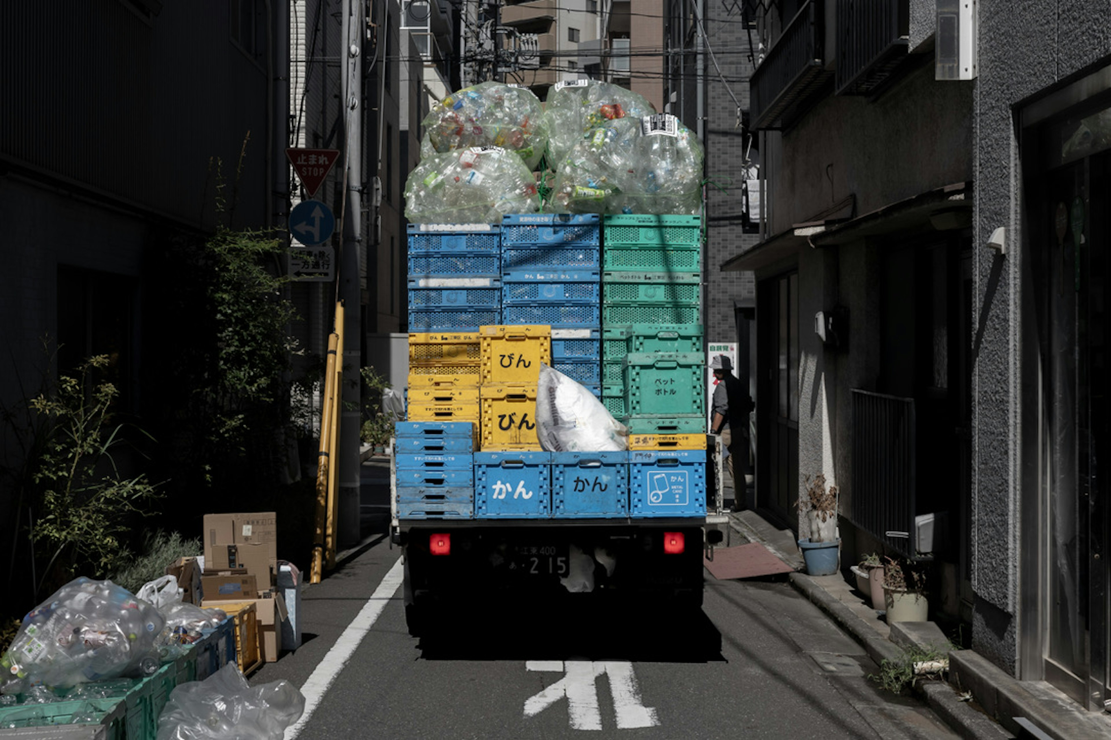 狹窄巷弄中裝滿藍色塑膠容器的垃圾收集車