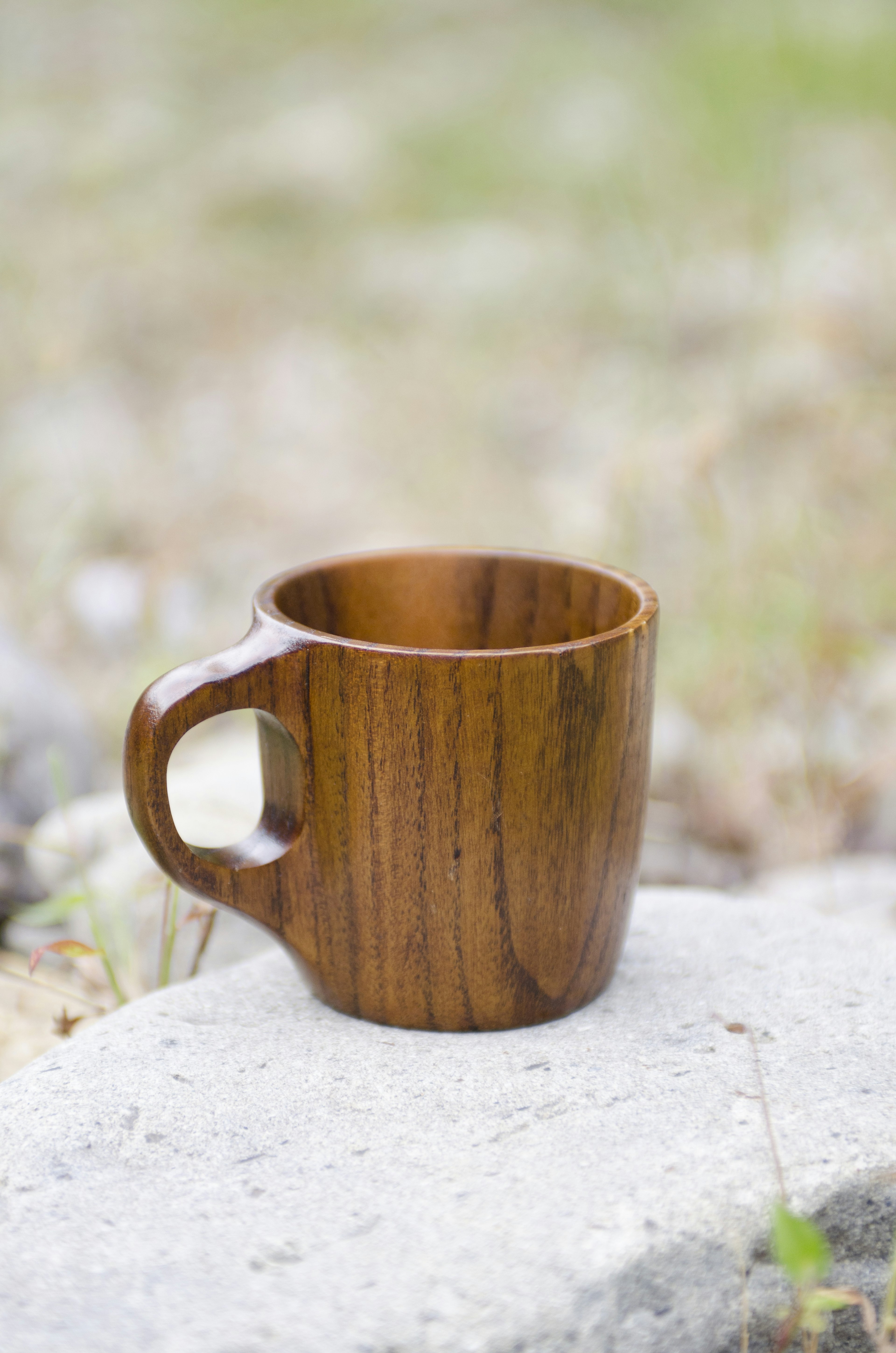 A wooden cup placed on a stone in a natural outdoor setting