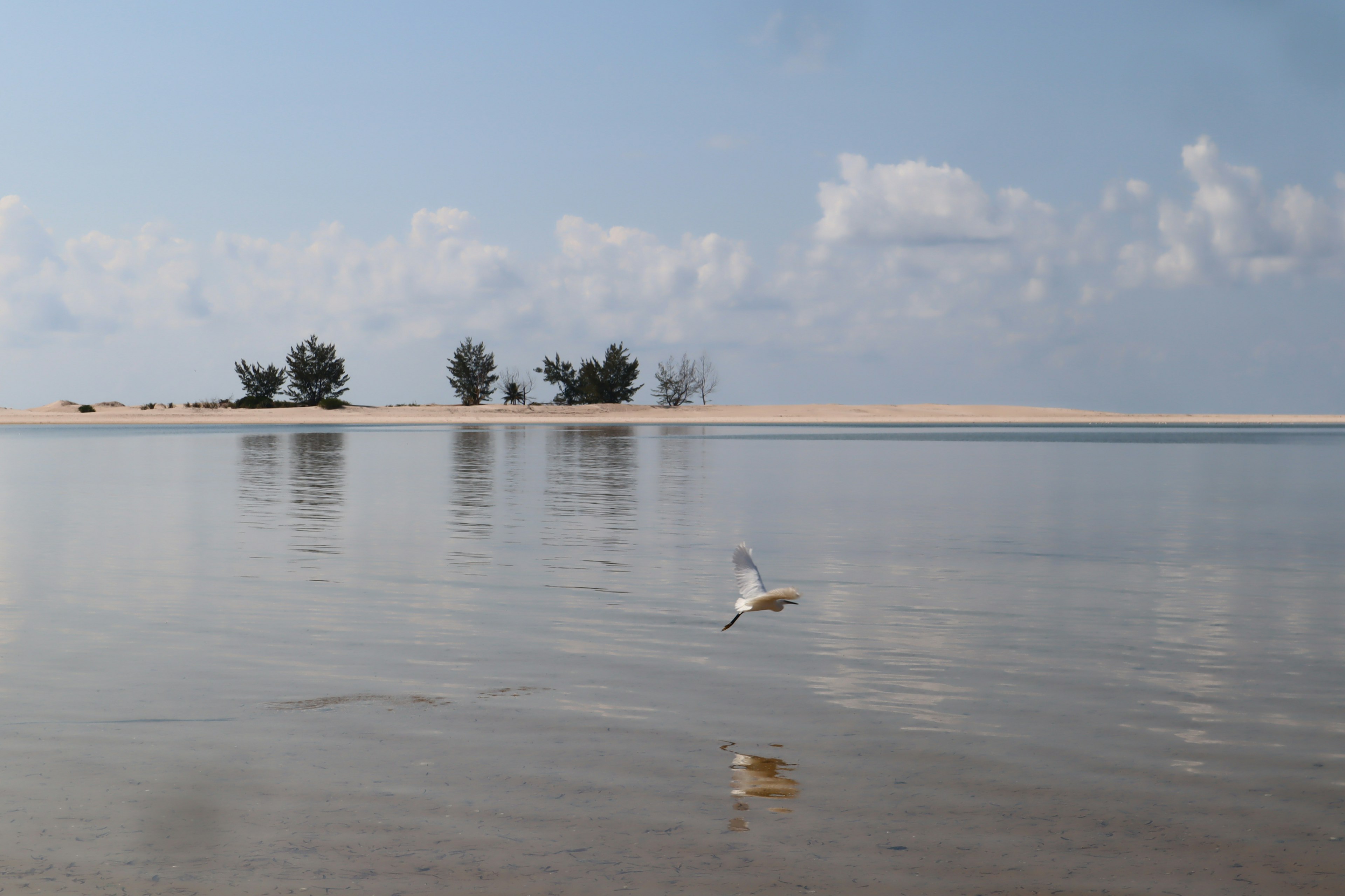 Pemandangan pantai yang indah dengan refleksi laut dan langit yang tenang