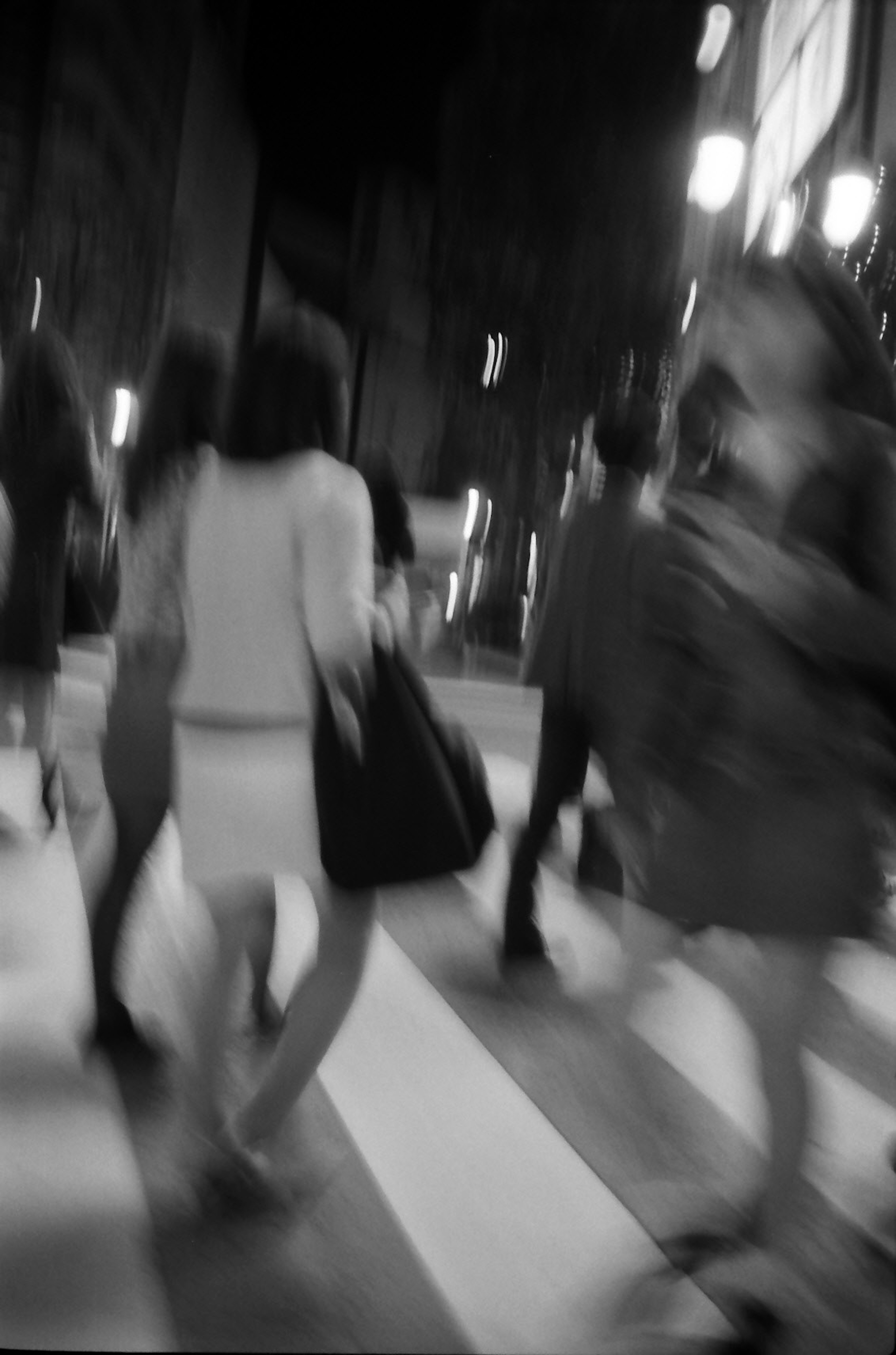 Motion blur of people crossing a crosswalk at night in a city