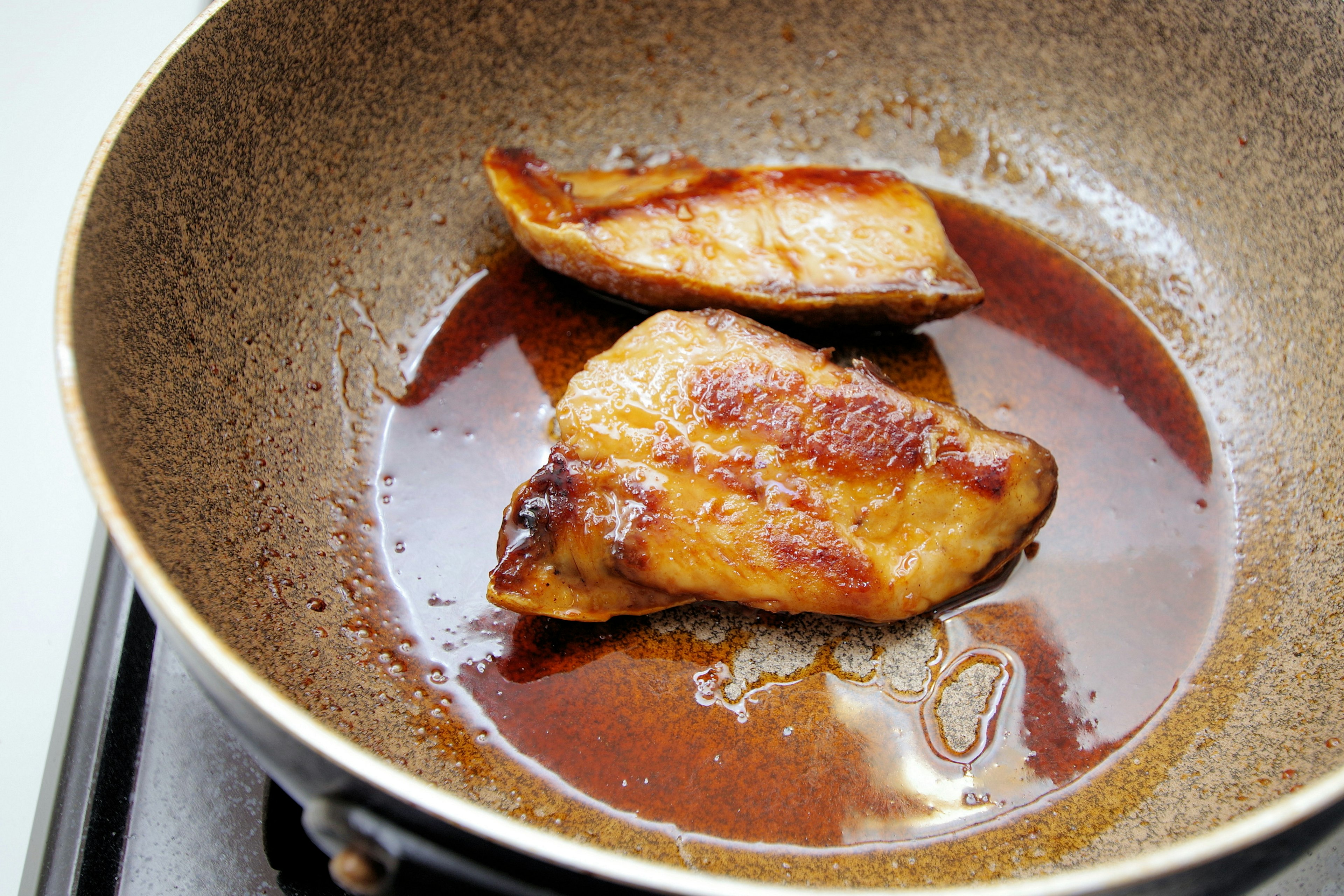 Filetes de pescado cocinándose en una sartén con salsa