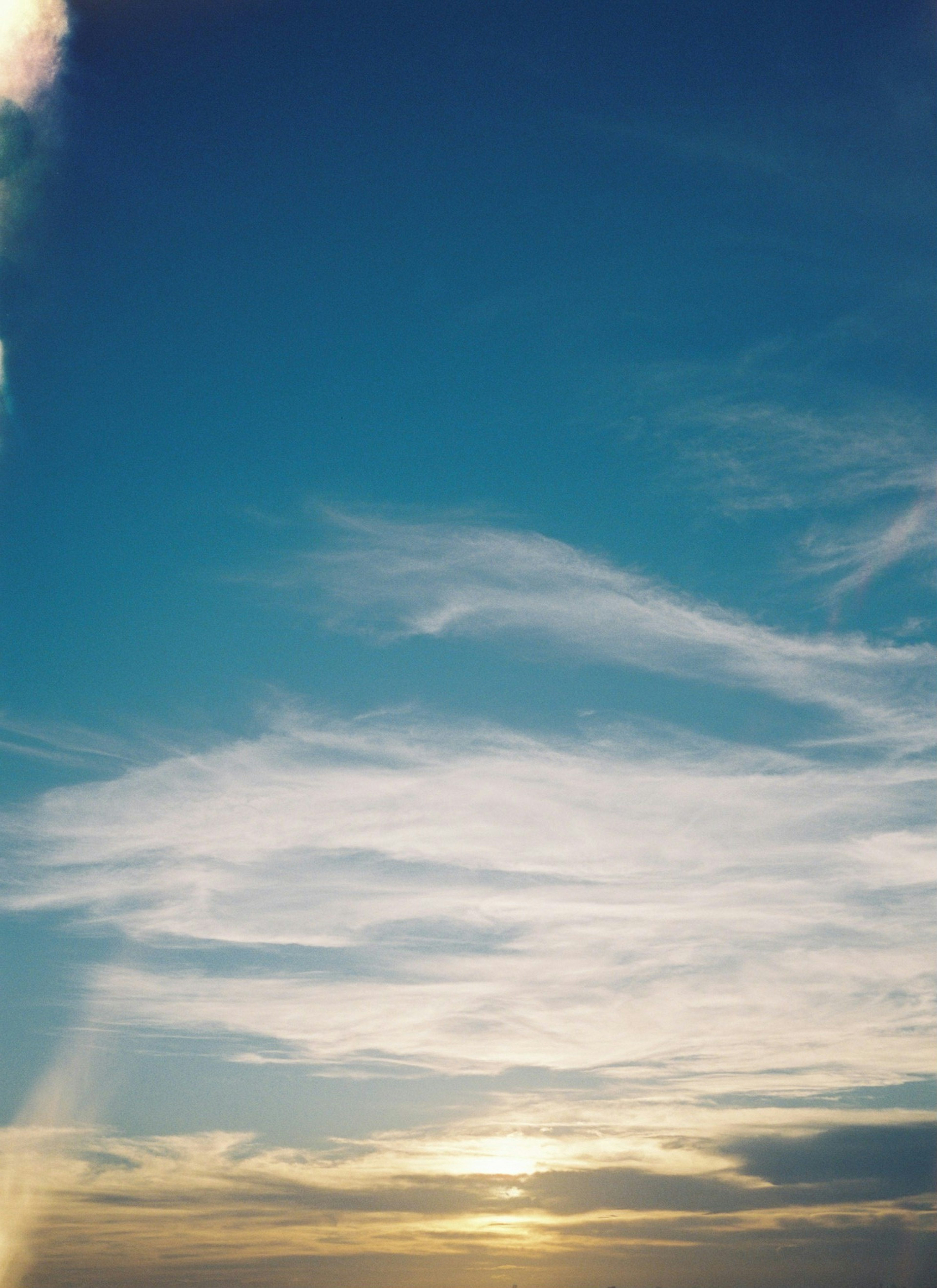 青空と雲の広がりの中に夕日