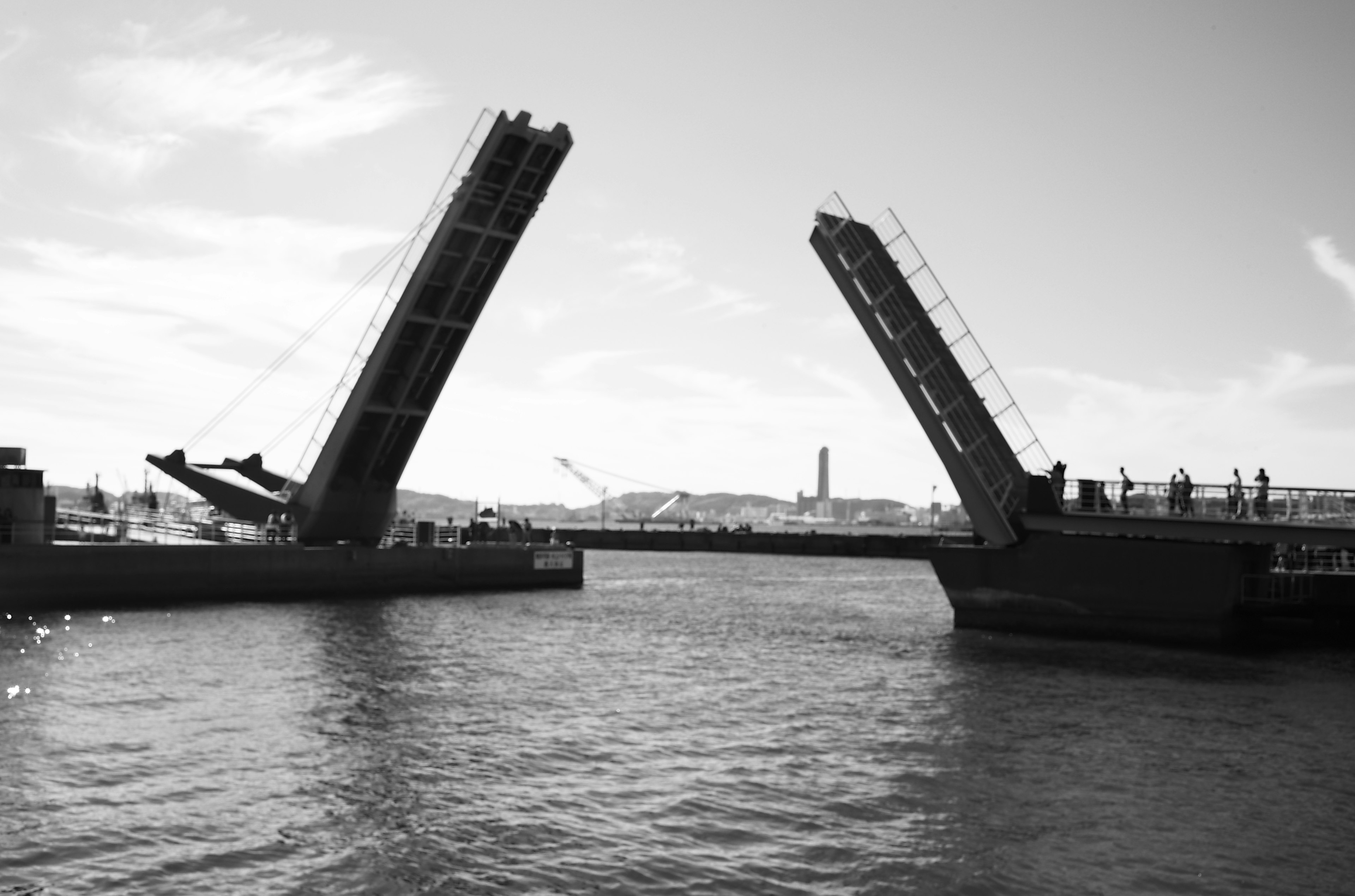 Dua jembatan yang membuka di atas air dengan refleksi di permukaan dalam hitam dan putih