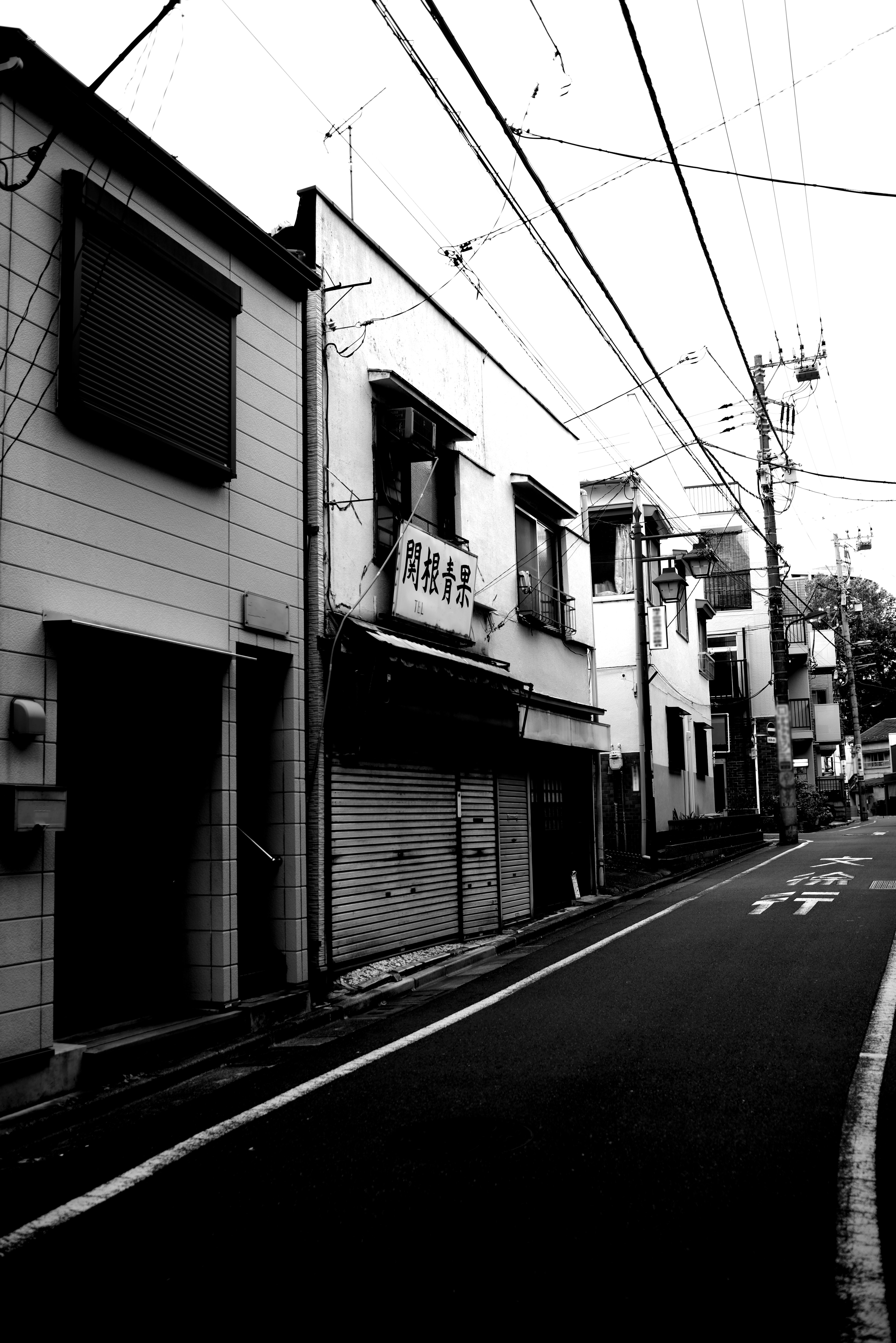 Calle en blanco y negro con edificios antiguos y líneas eléctricas