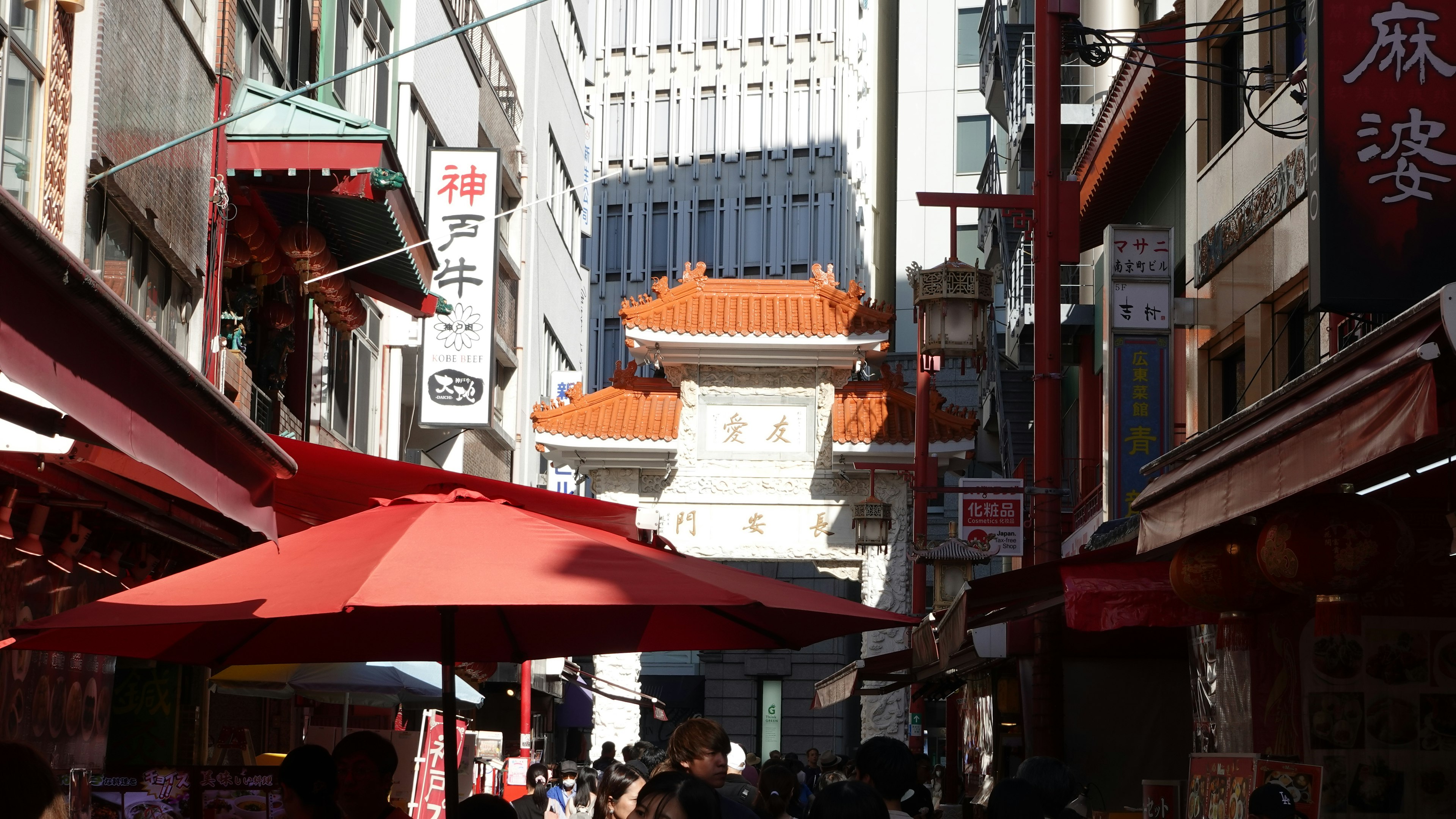 Belebte Straßenszene mit roten Sonnenschirmen und Chinatown-Architektur