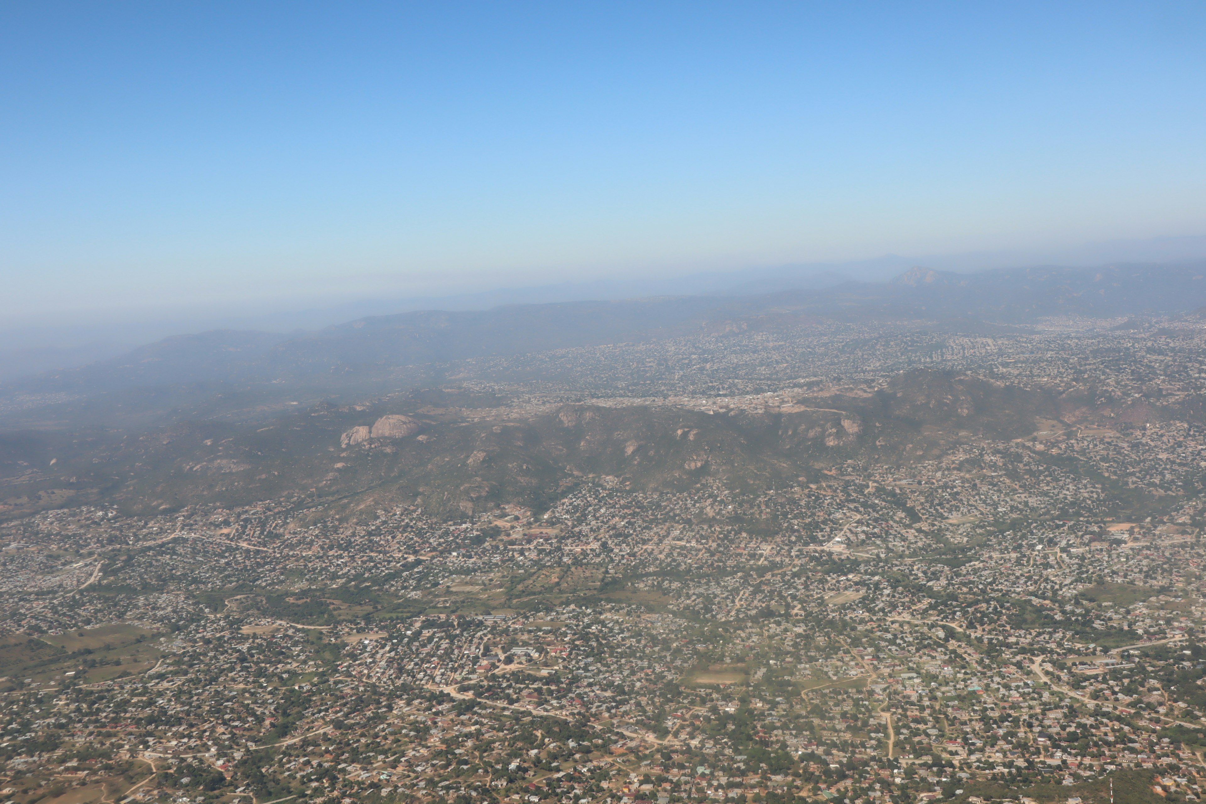 Vista aerea di un paesaggio urbano con cielo blu e montagne lontane