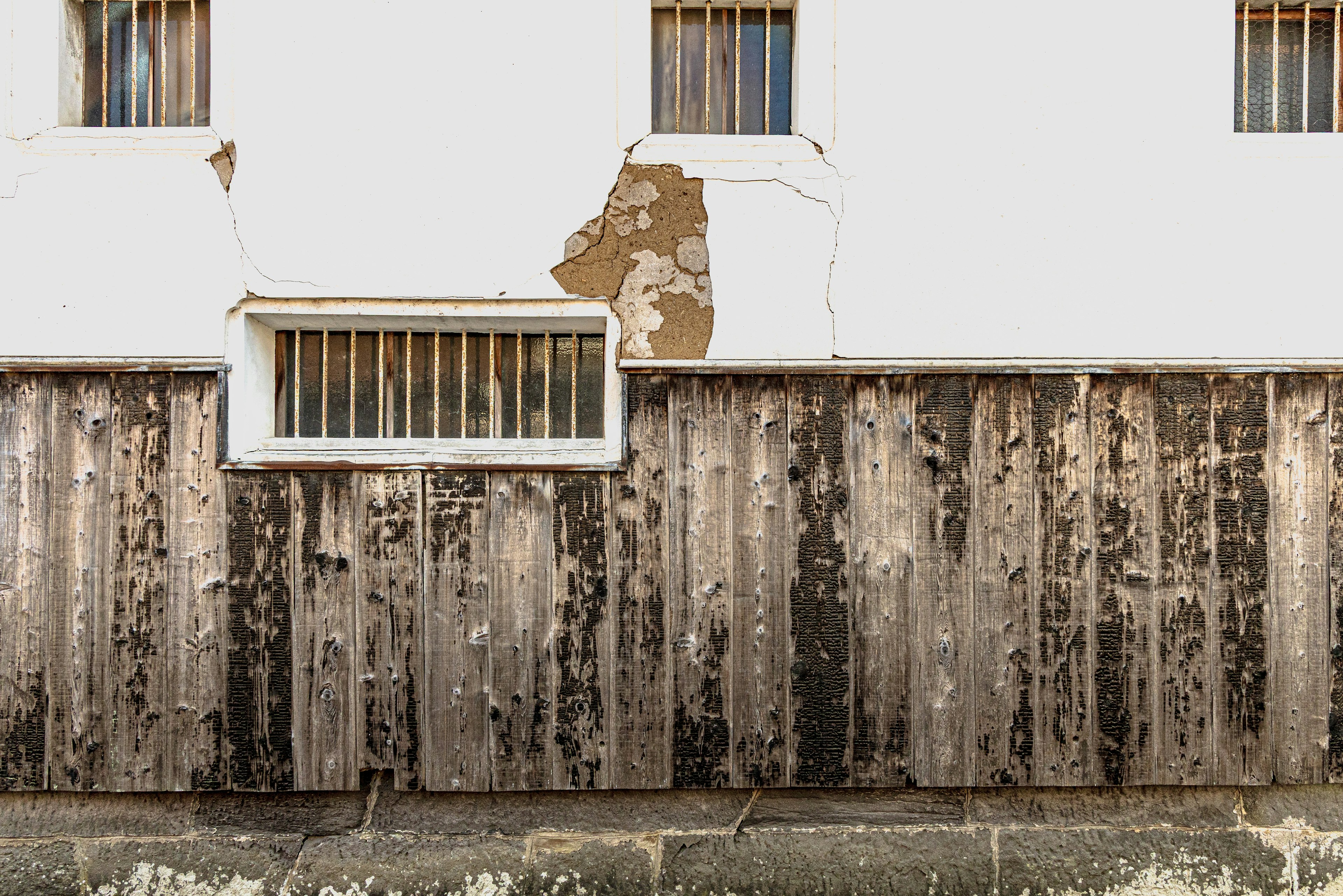 sección de un viejo edificio con una pared blanca y una cerca de madera