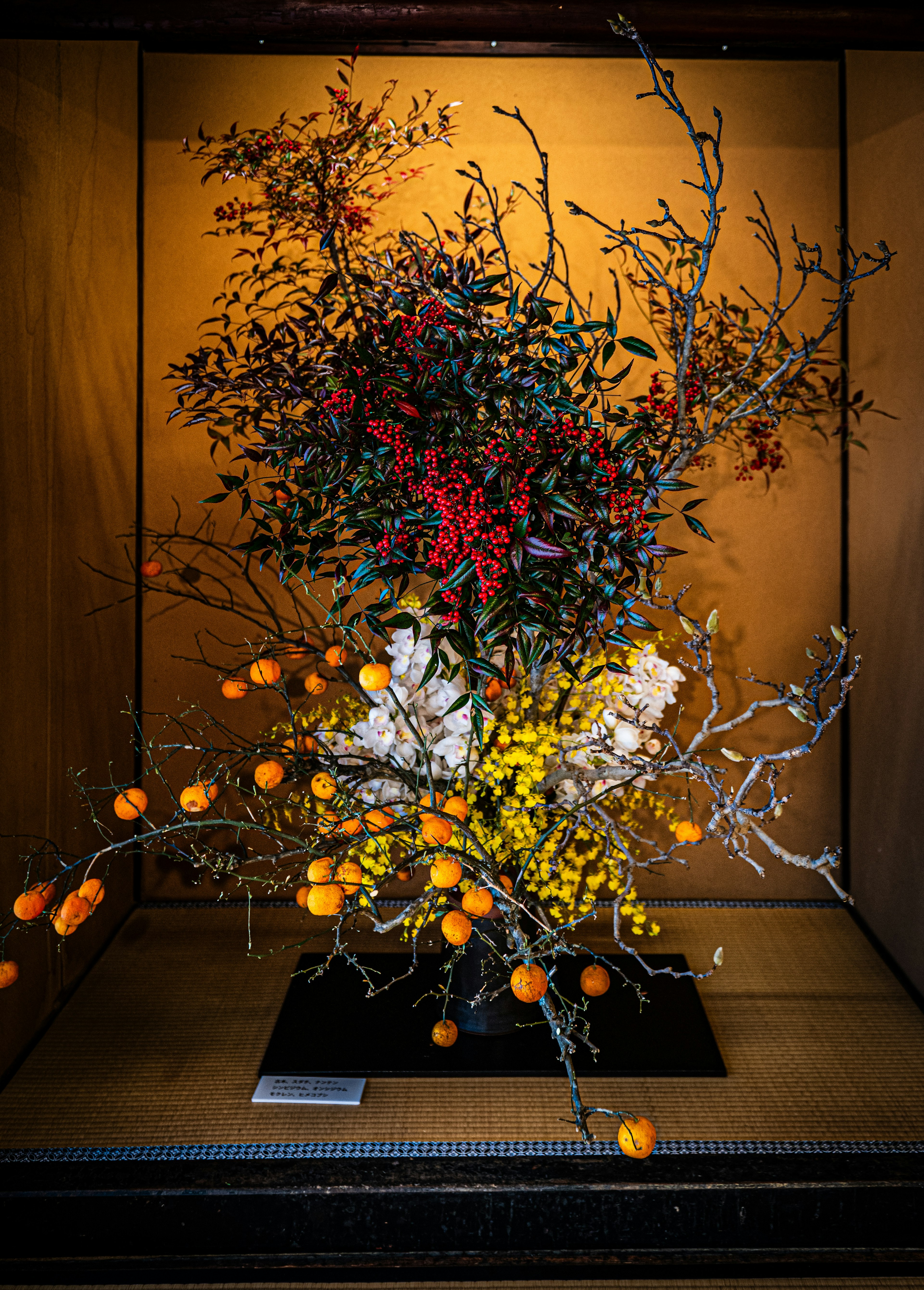 Colorful floral arrangement featuring orange fruits and various branches