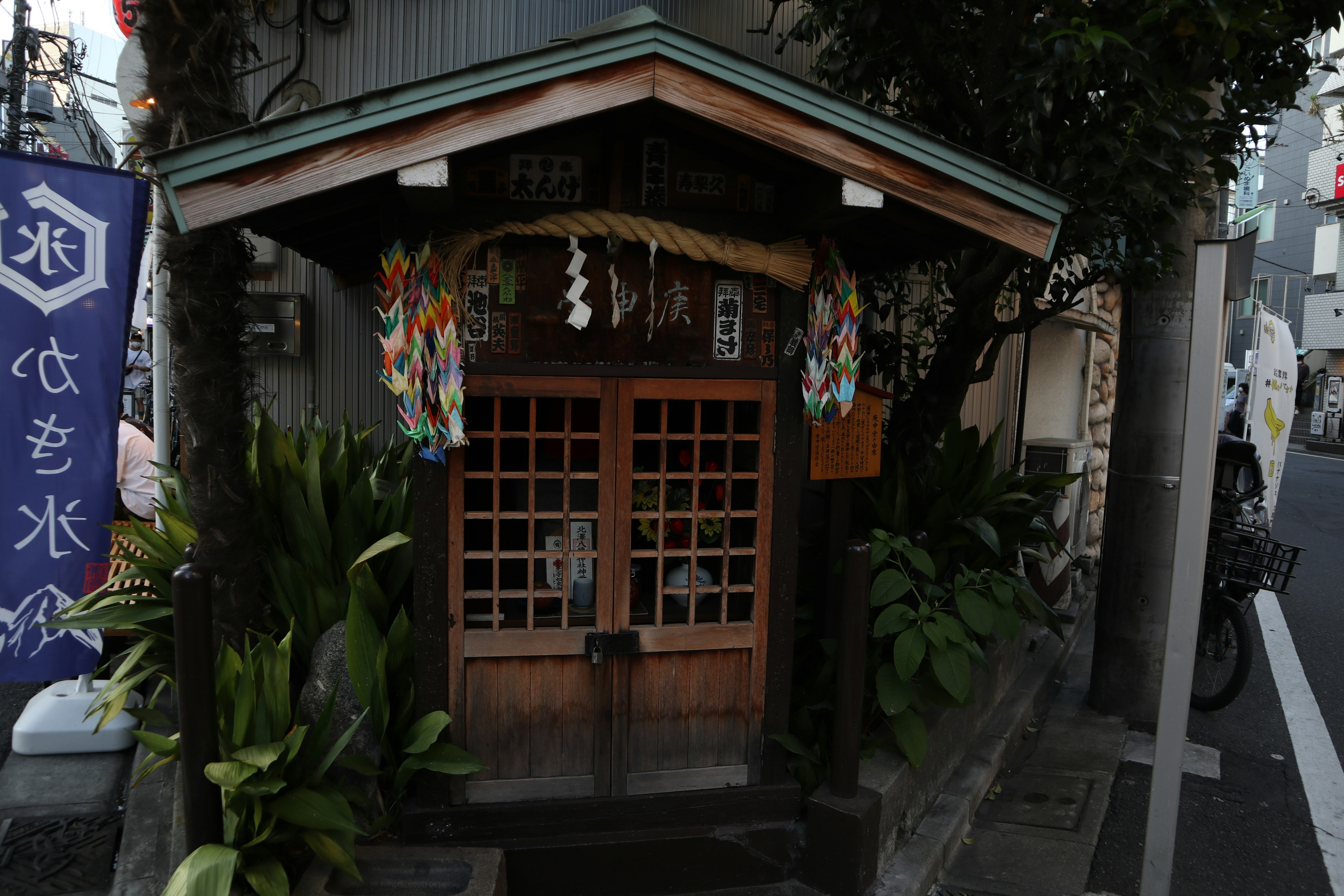 Eingang eines traditionellen japanischen Gebäudes umgeben von Grün Holztür mit dekorativem Dach