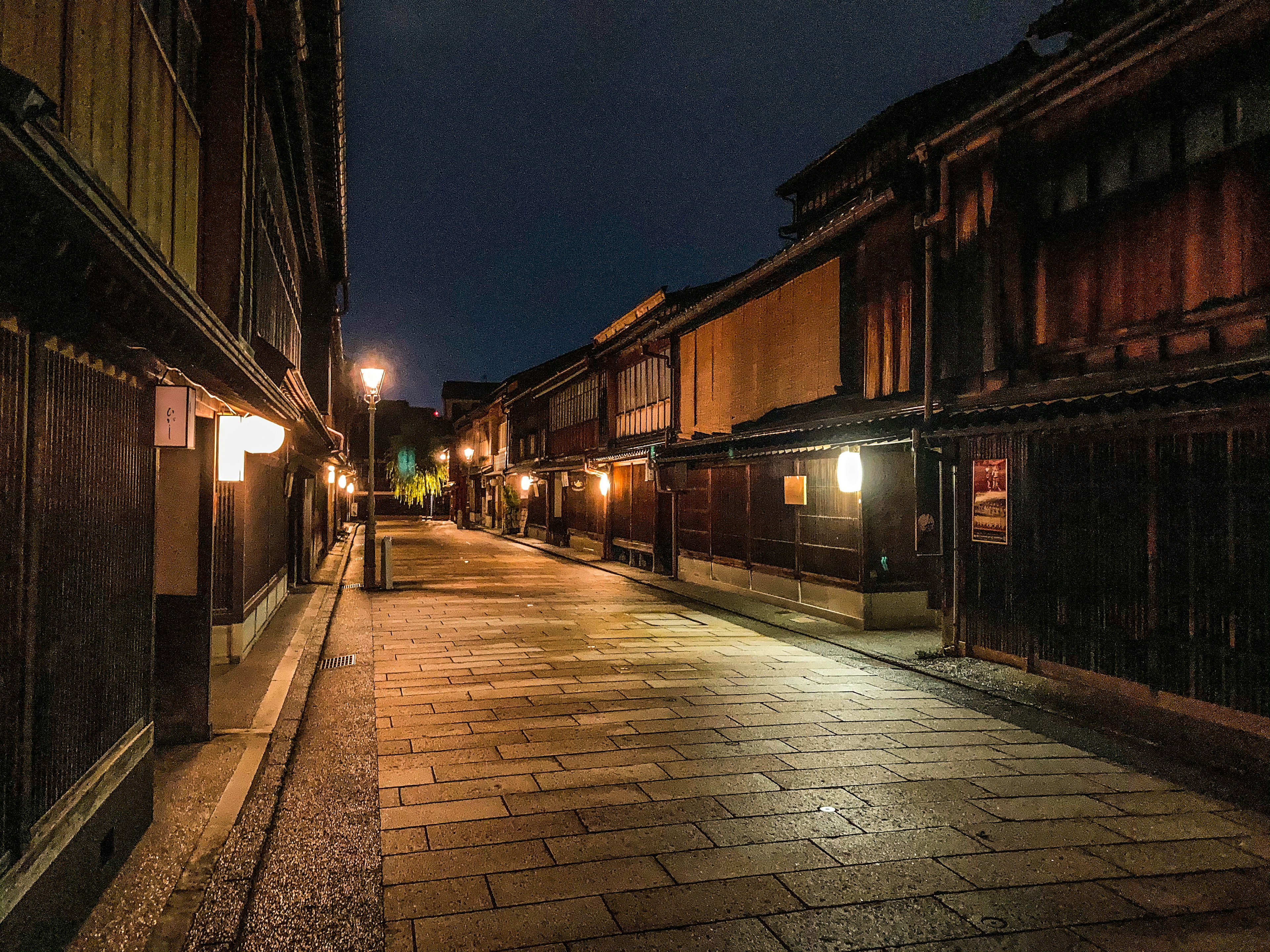 Ruhige Straße bei Nacht mit traditionellen Holzbauten und Kopfsteinpflaster