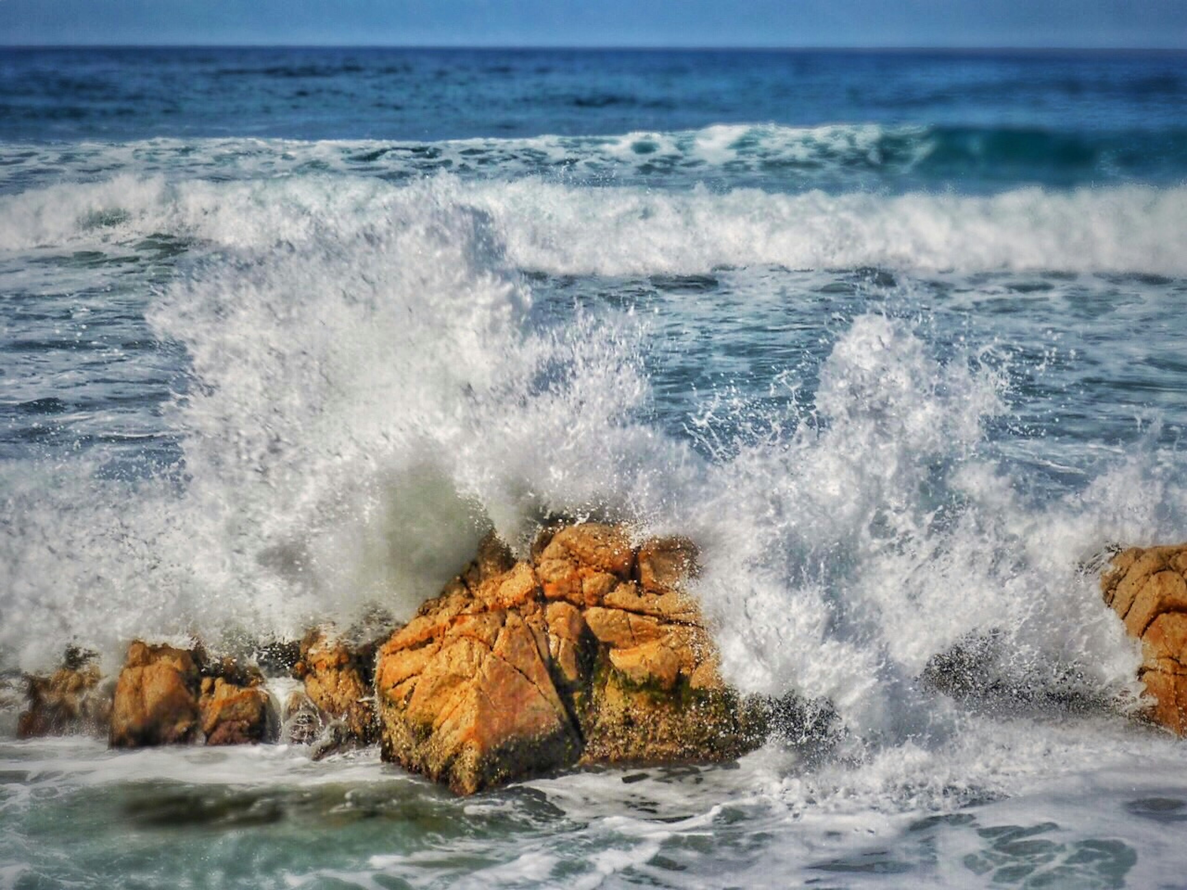 Olas rompiendo contra rocas en una escena costera