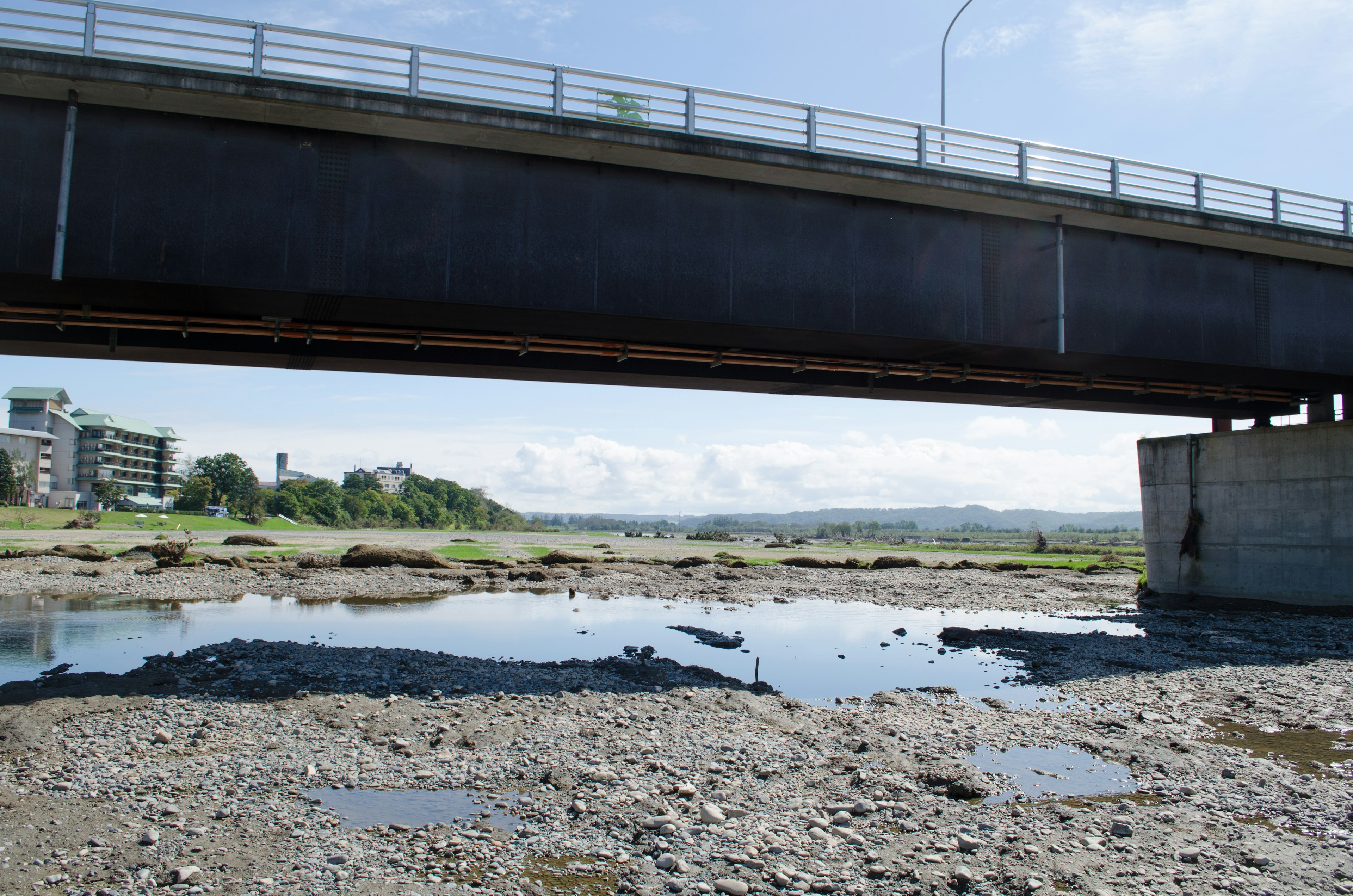 Pfütze und felsiger Uferbereich unter einer Brücke