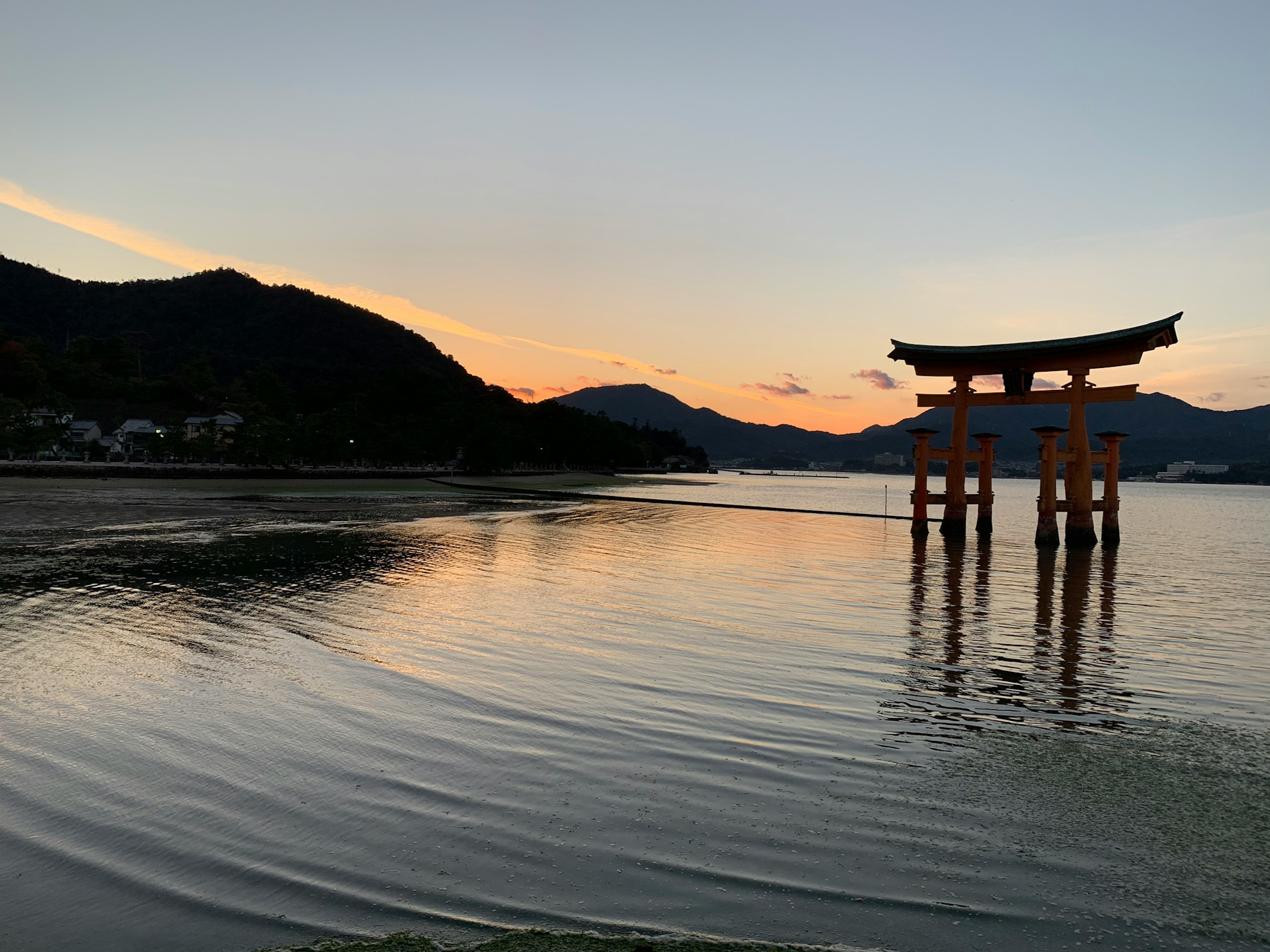 美しい夕焼けの中に立つ鳥居と静かな水面