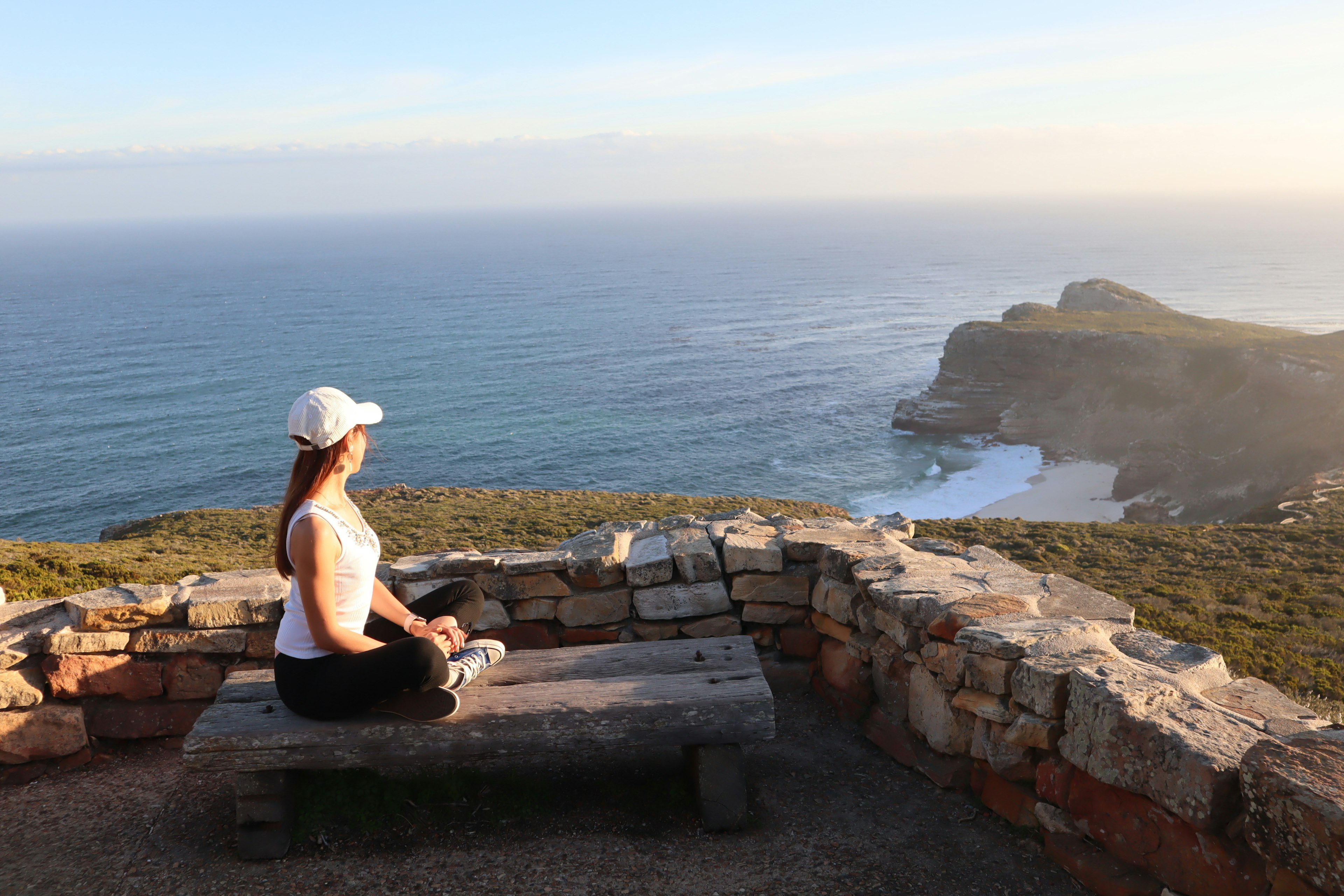 Woman sitting on a stone bench overlooking the ocean