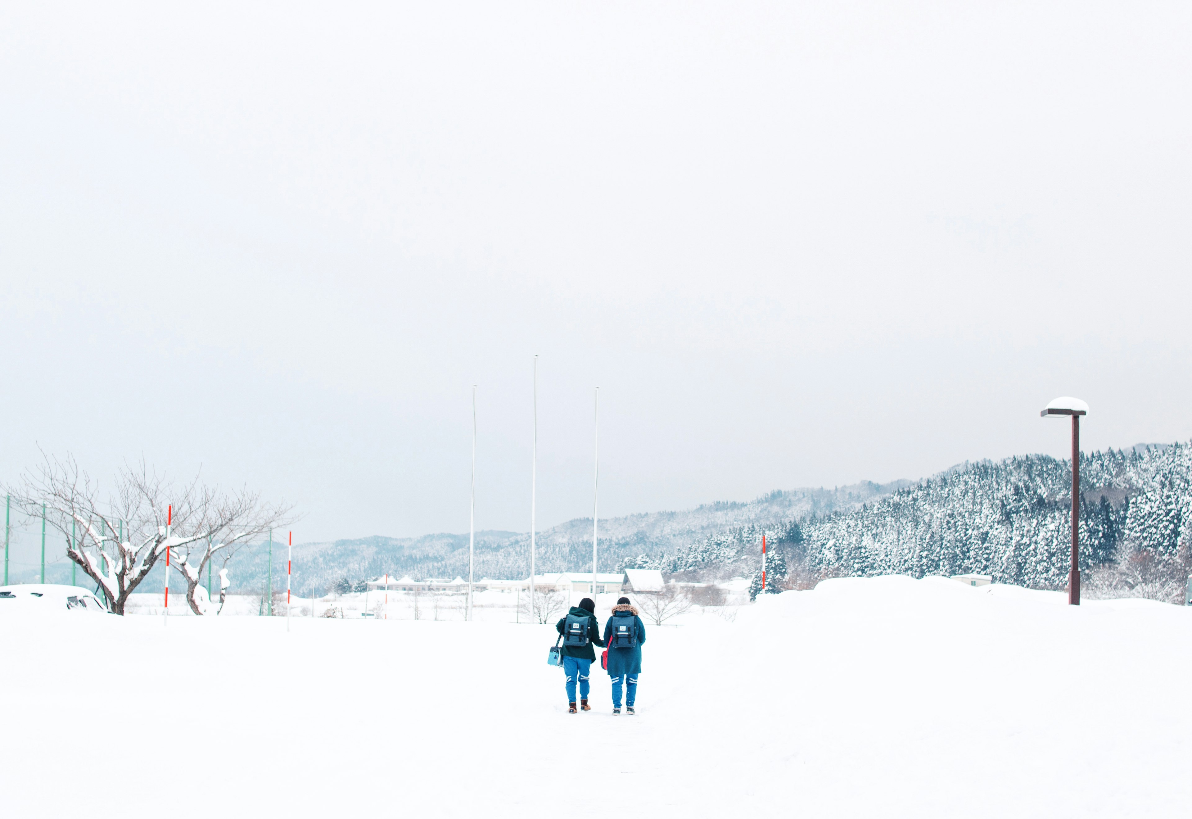 雪に覆われた道を歩く二人の人物