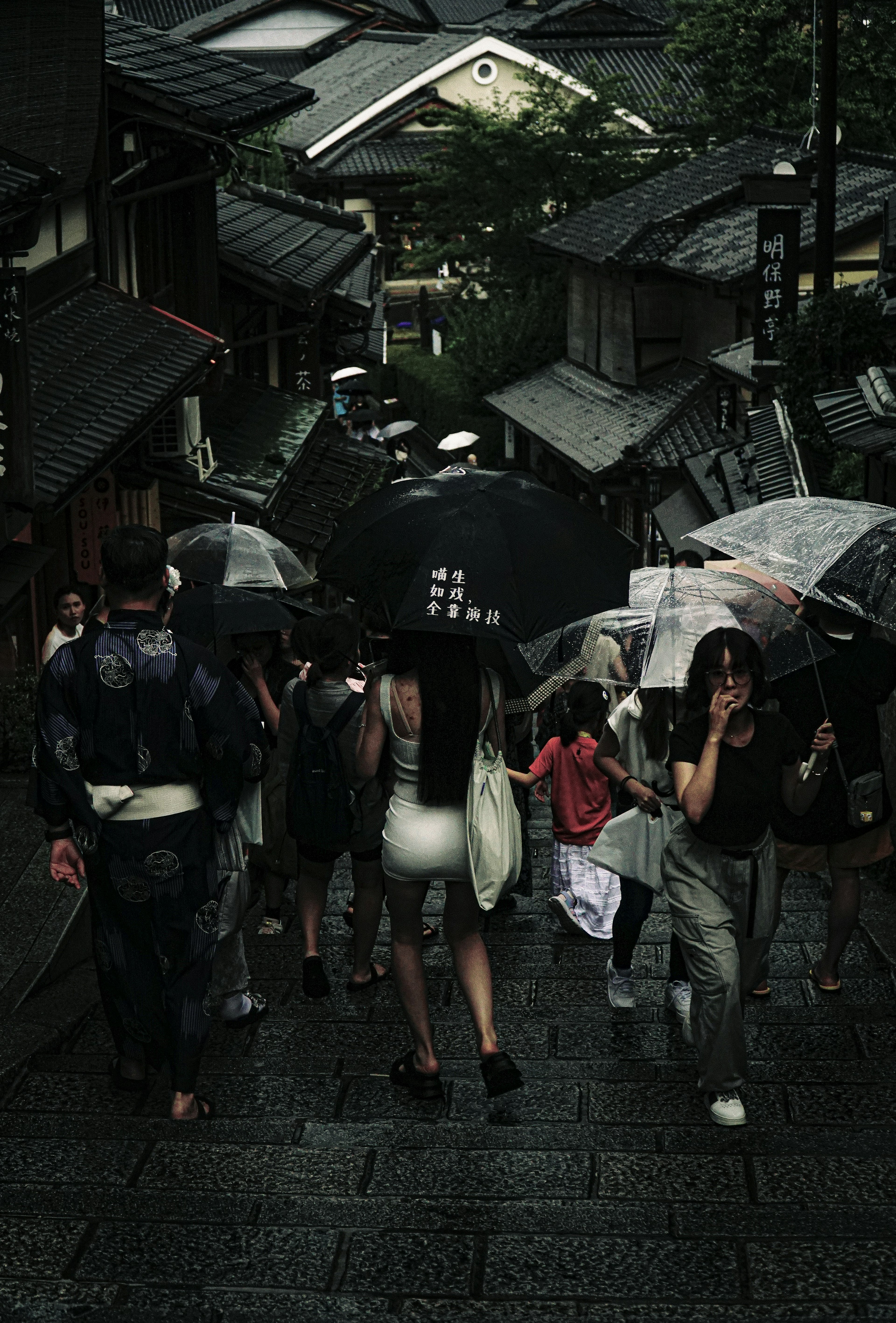 雨の中で傘を持っている人々が階段を上る京都の風景