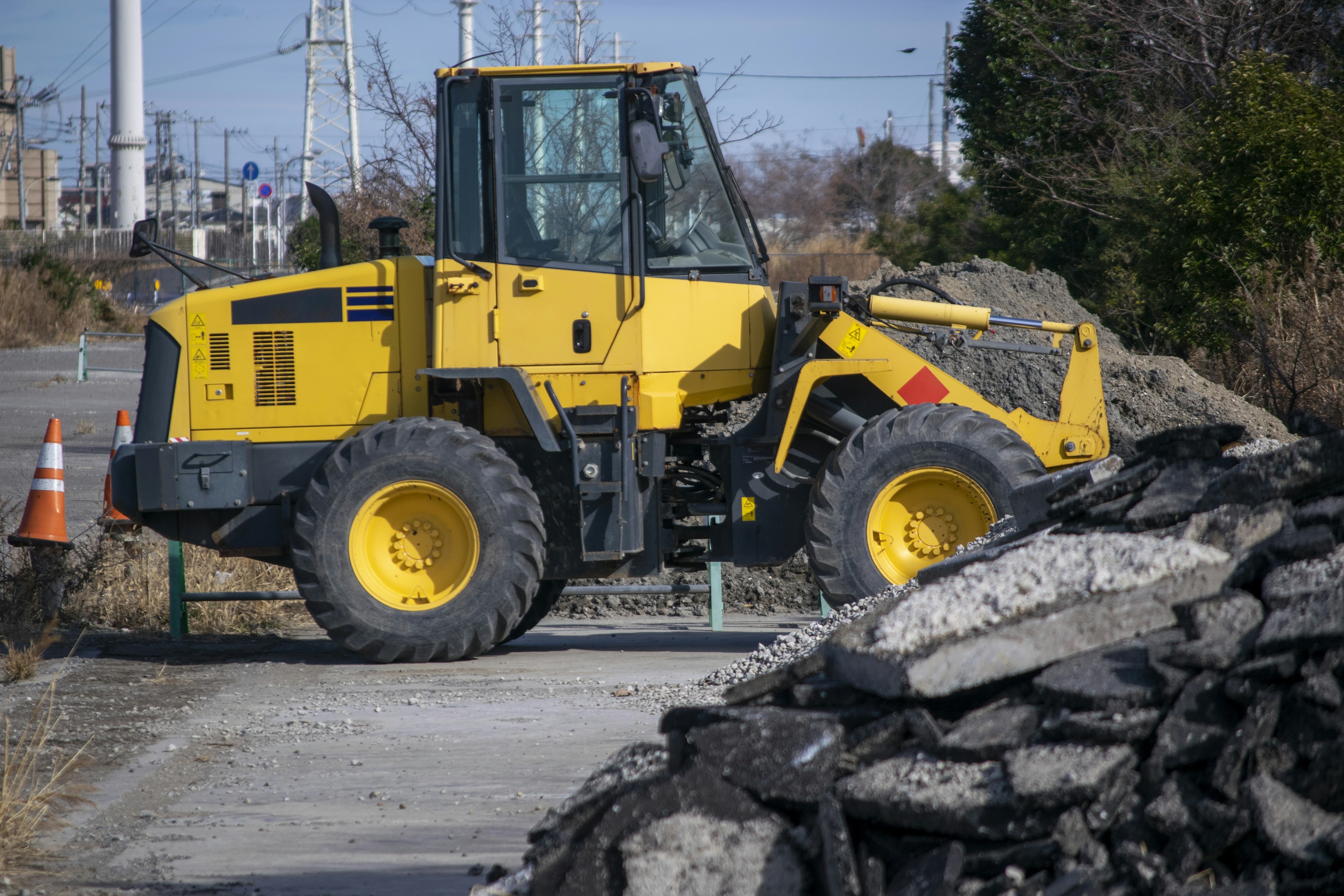 Yellow construction vehicle digging at the side of a road