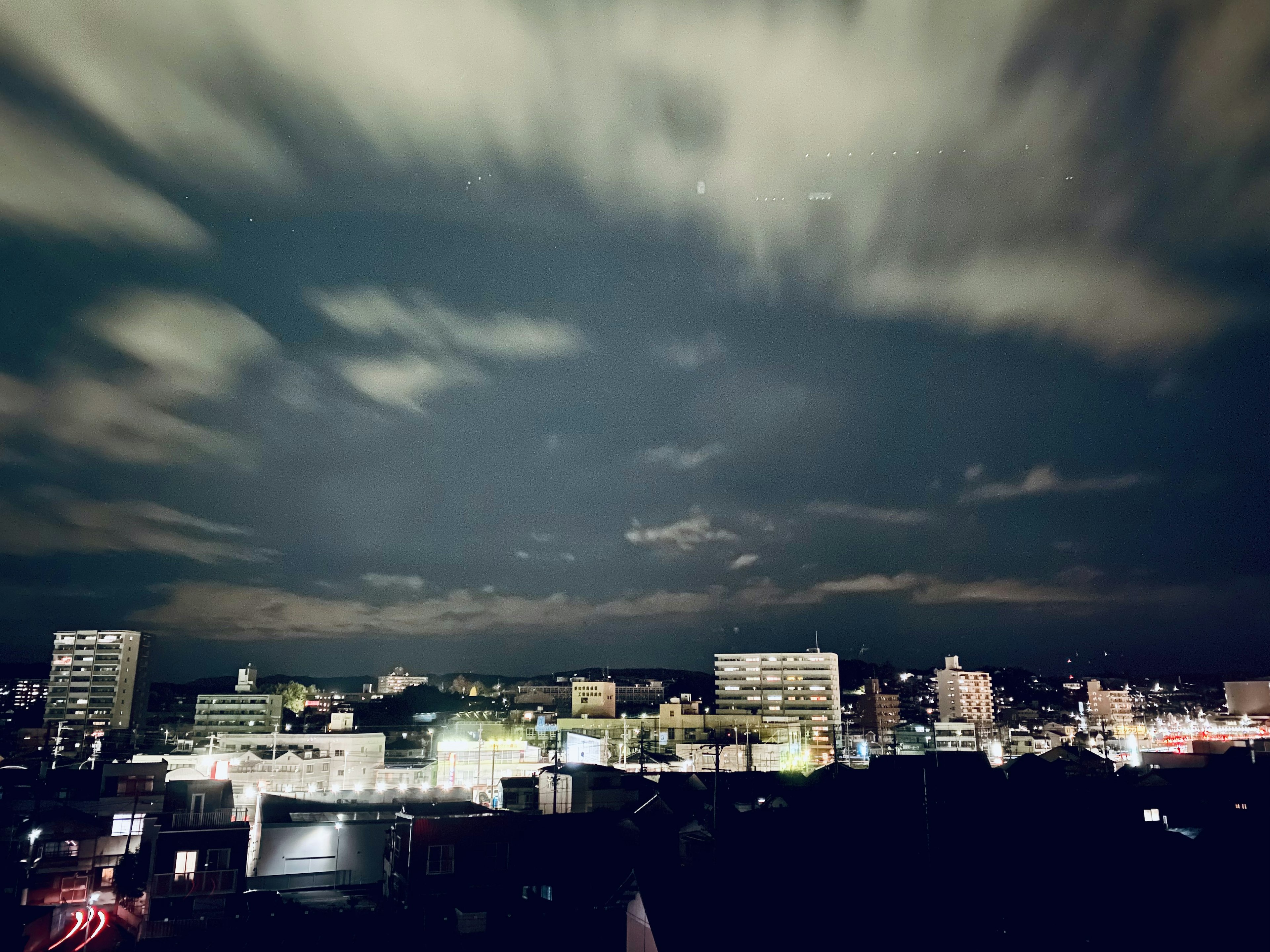 Night cityscape featuring bright buildings and cloudy sky