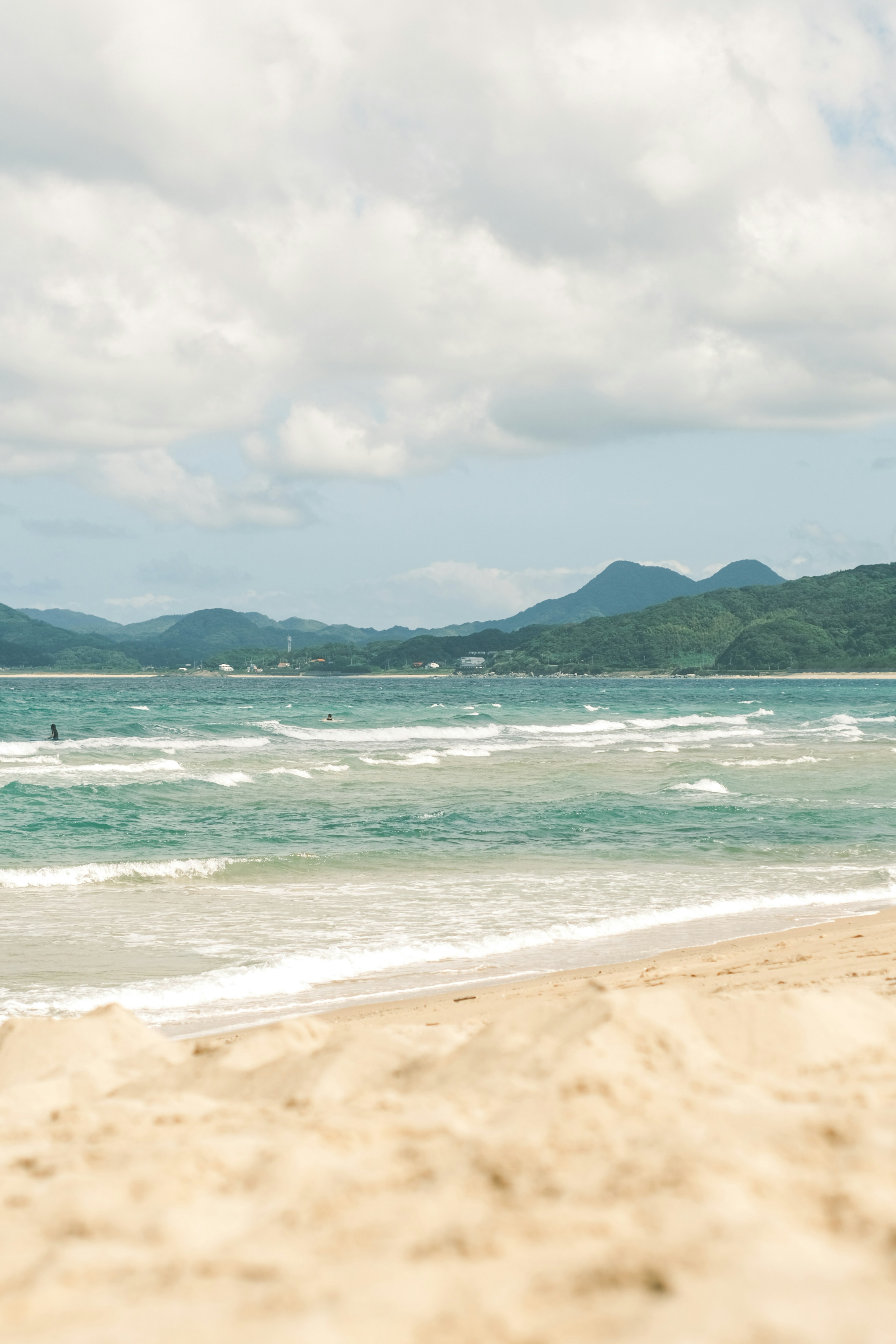 Scenic beach view with soft sand and blue waves under cloudy sky