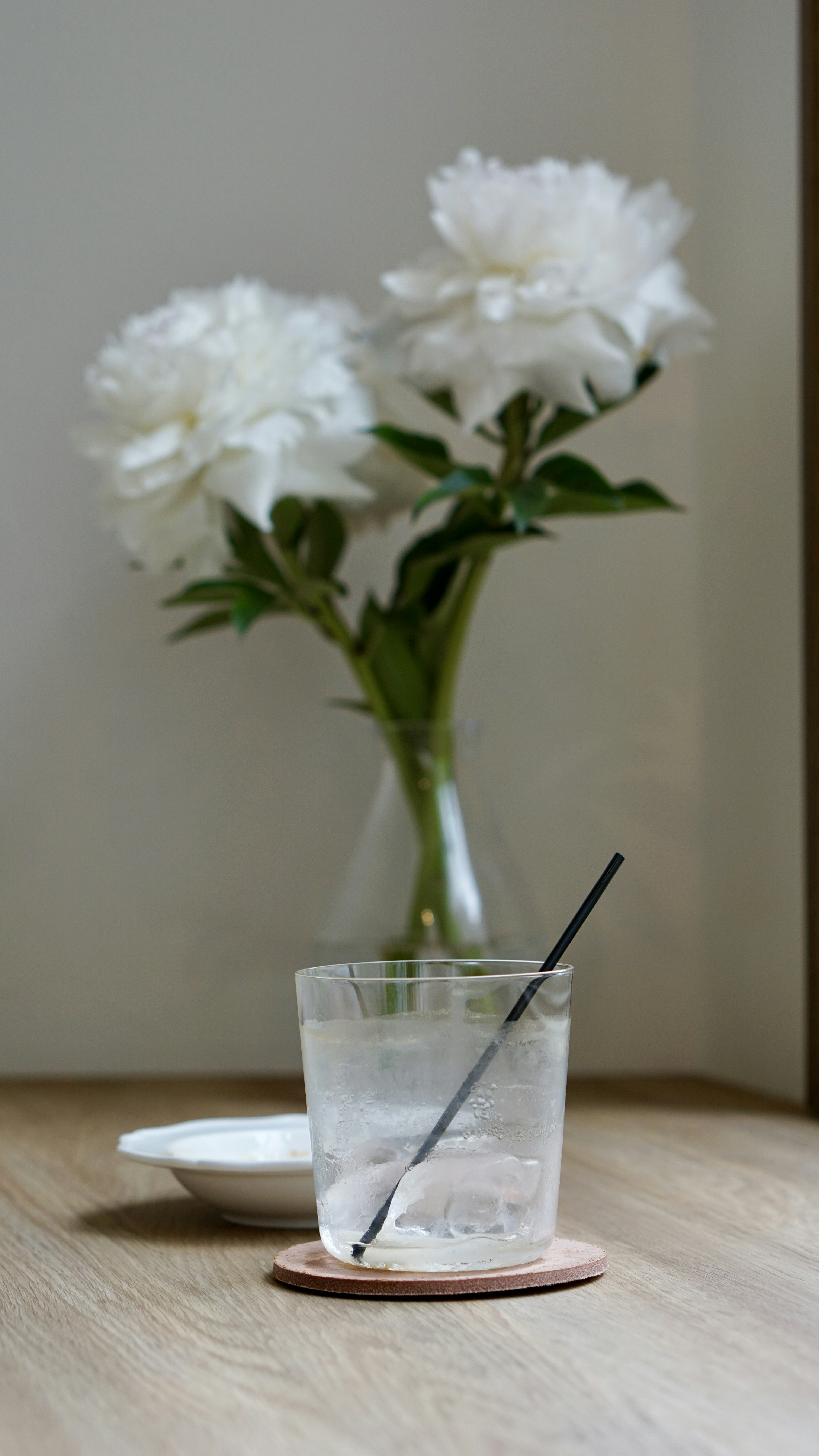 白い花が飾られた花瓶と透明なグラスの飲み物