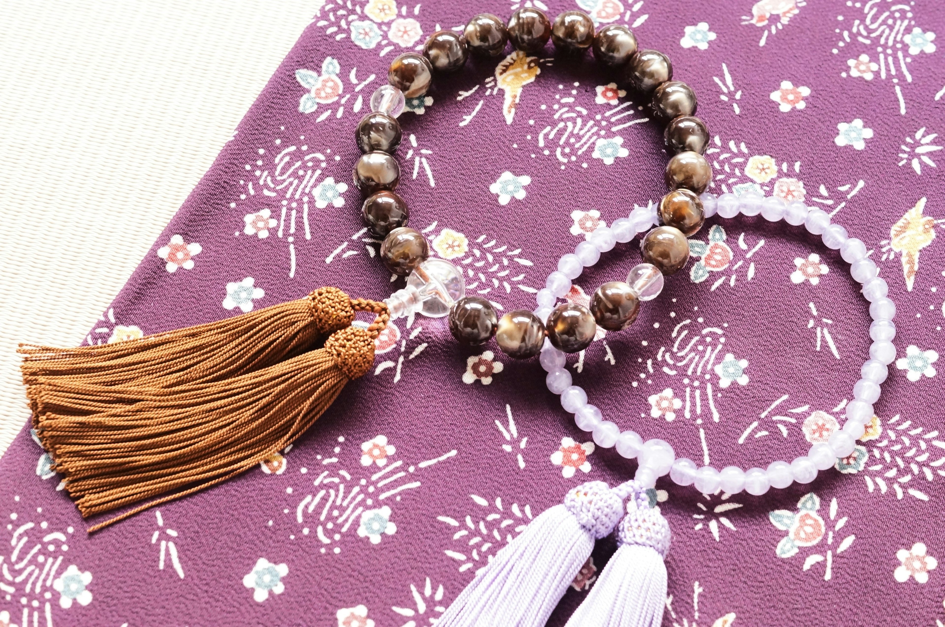 Image de deux bracelets avec des pompons posés sur un tissu violet à motifs