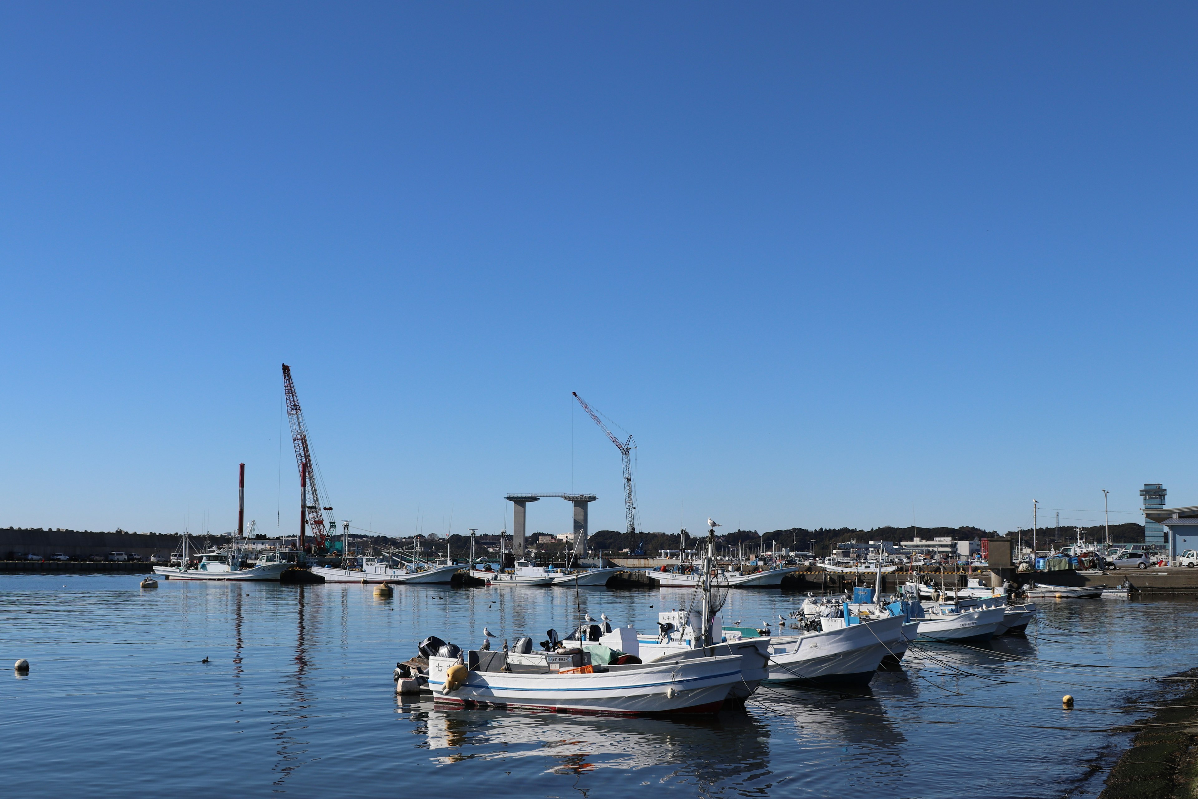 Small boats docked in a calm harbor under a blue sky