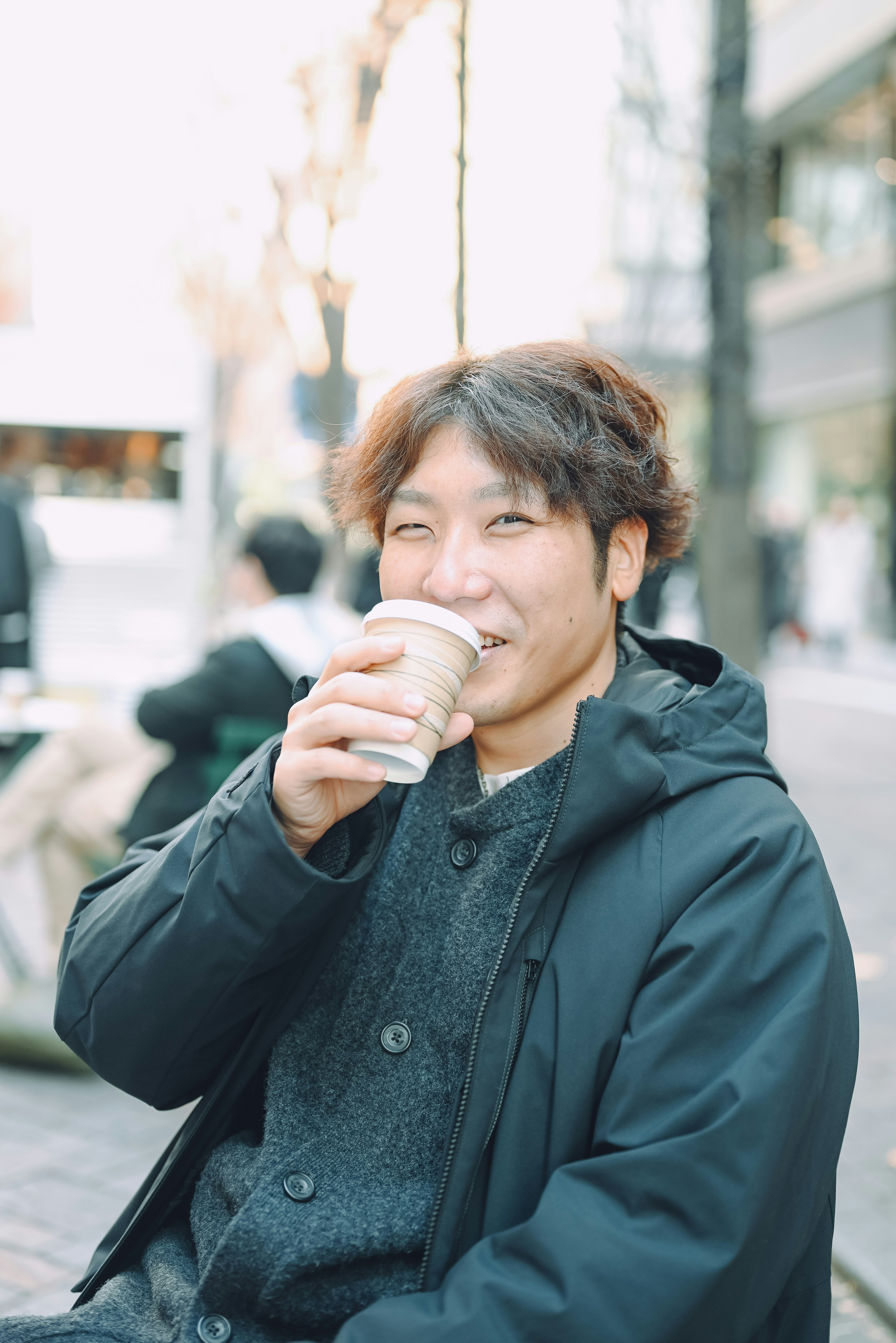 笑顔の男性がコーヒーを飲んでいる街のシーン