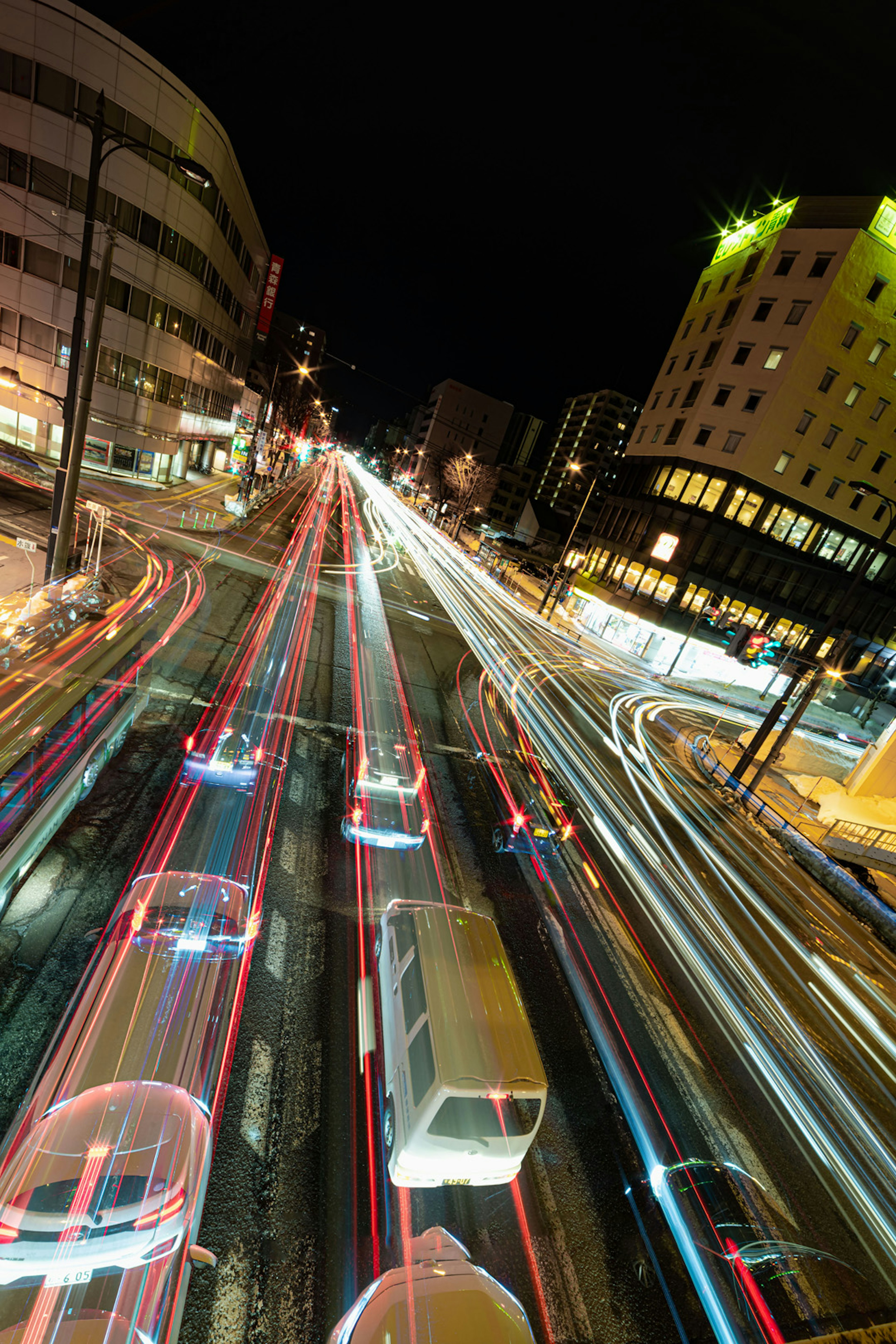 Nachtsicht des Stadtverkehrs mit sichtbaren Lichtspuren von fahrenden Fahrzeugen