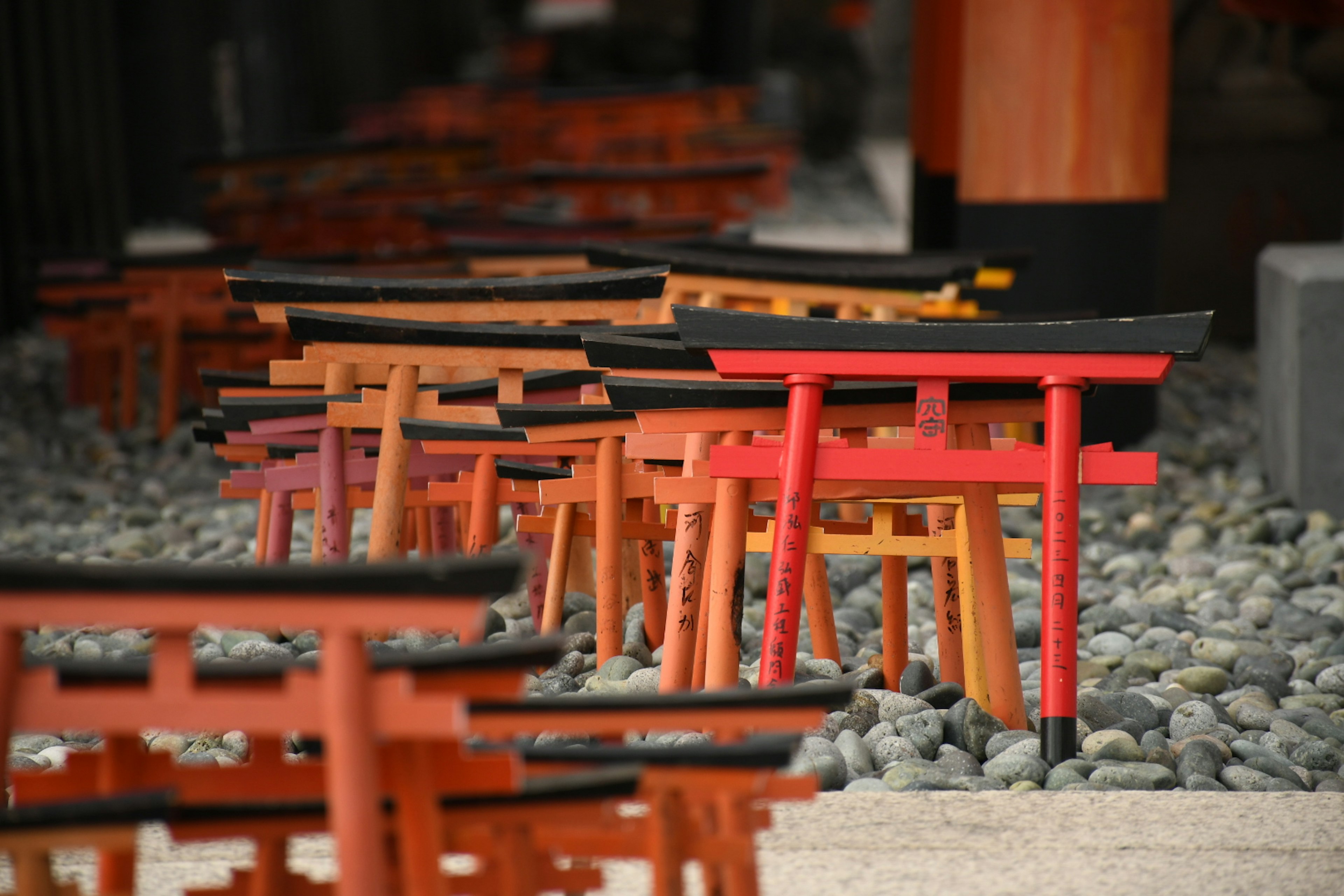 Rows of red and black torii gates arranged on stones